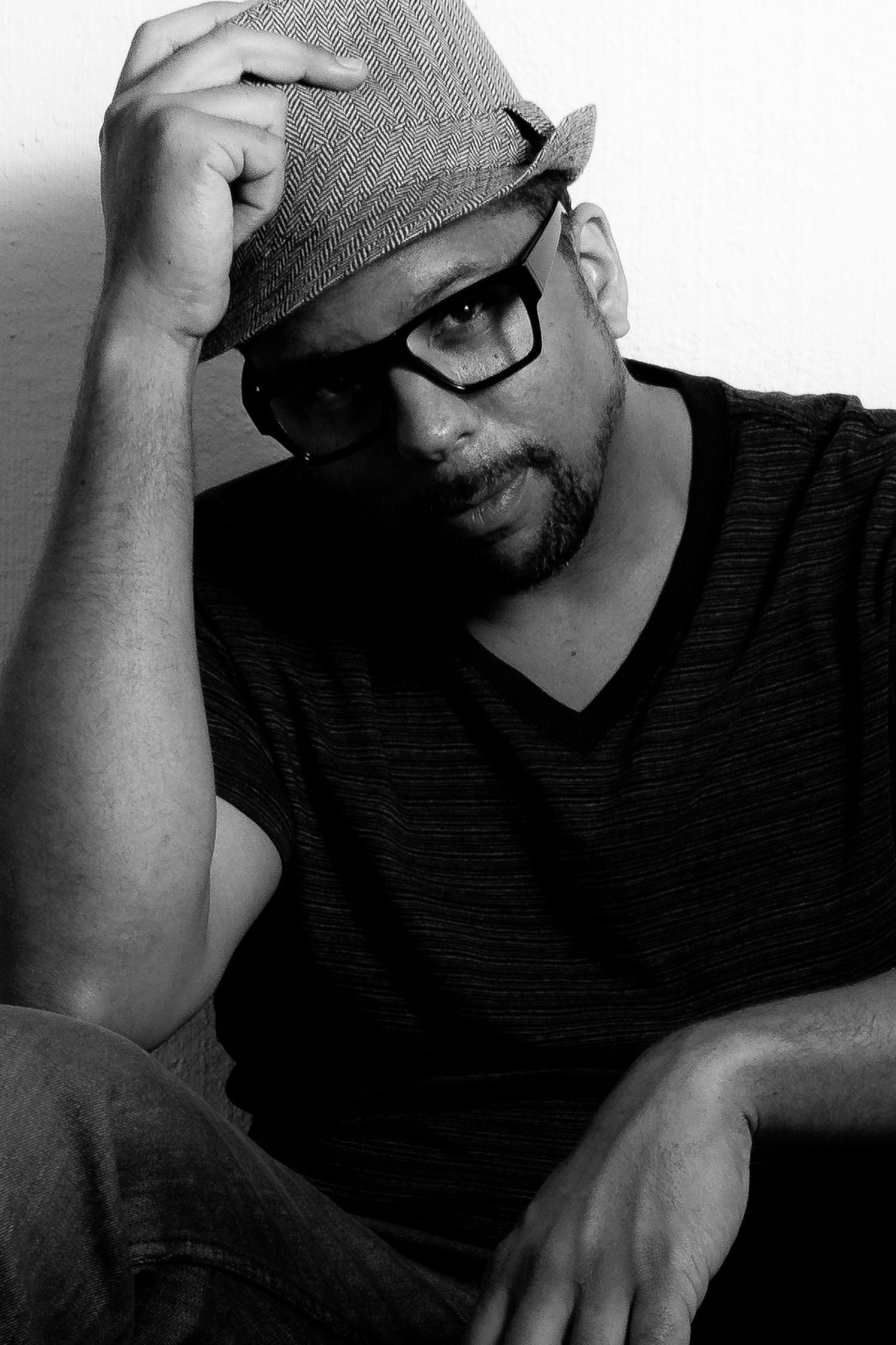Black-and-white portrait of a man in glasses resting a hand on his head.