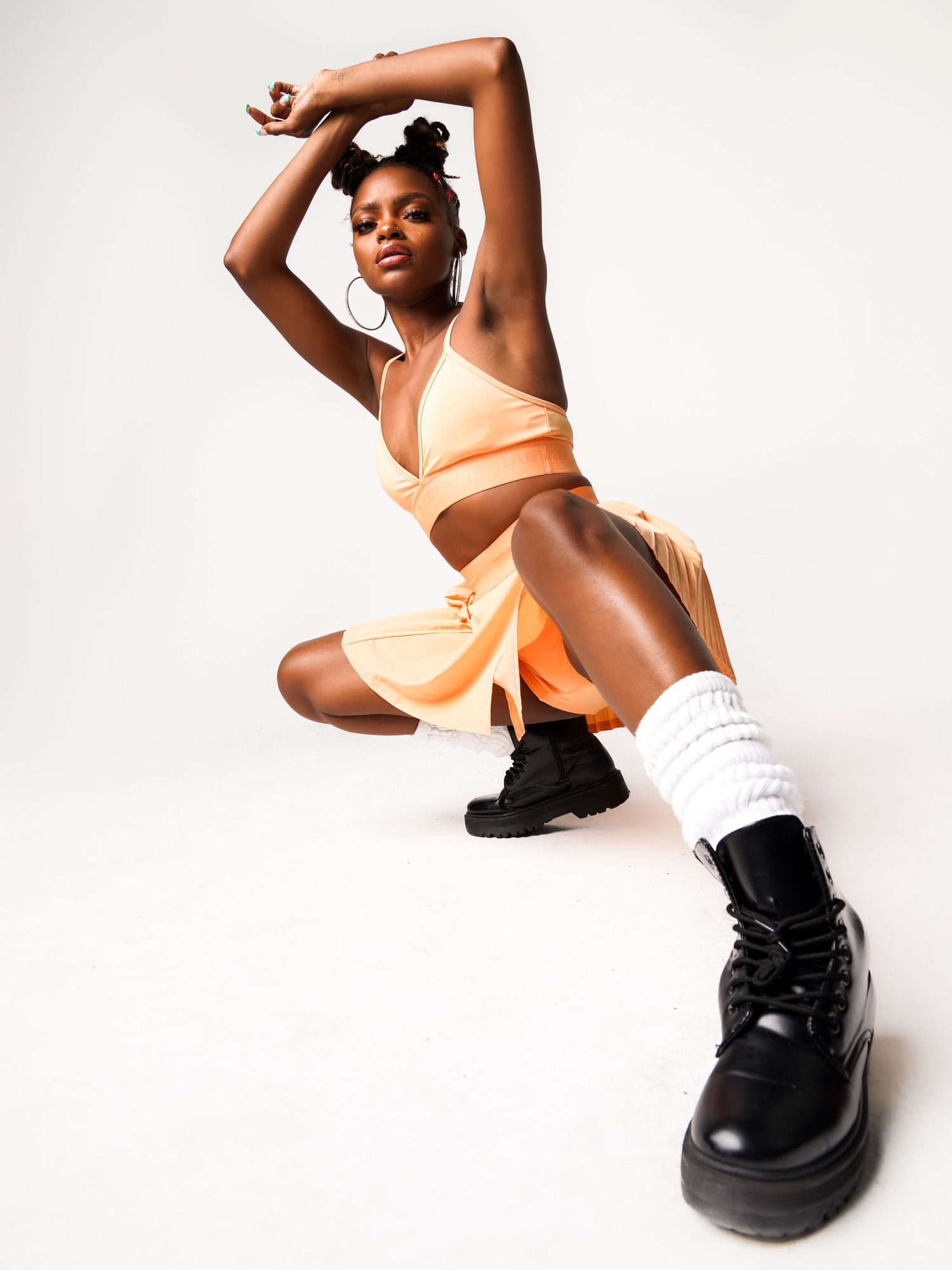 Fashion portrait of a woman in white posing with bold black boots.