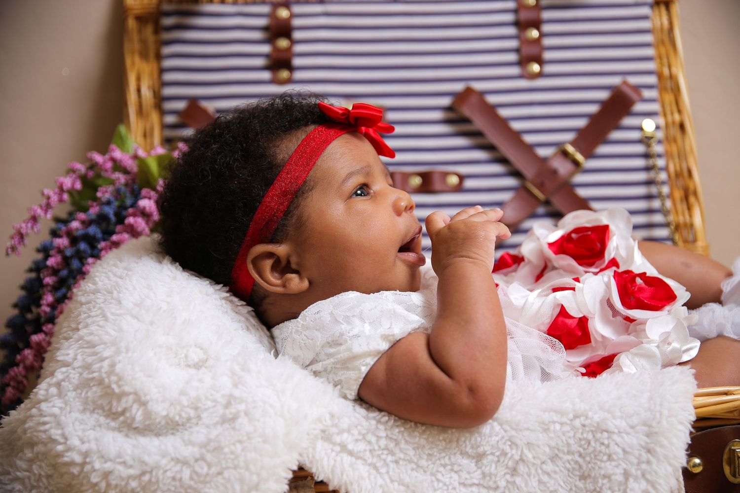 Baby in a festive holiday setting reaching toward red-and-white decorations.