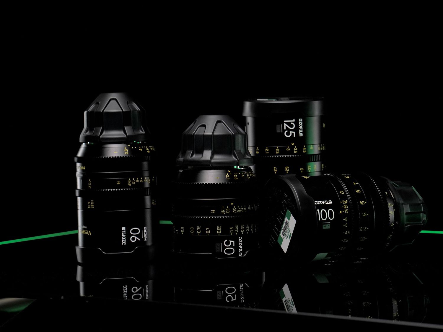 Professional cinema lenses arranged against a reflective black background.