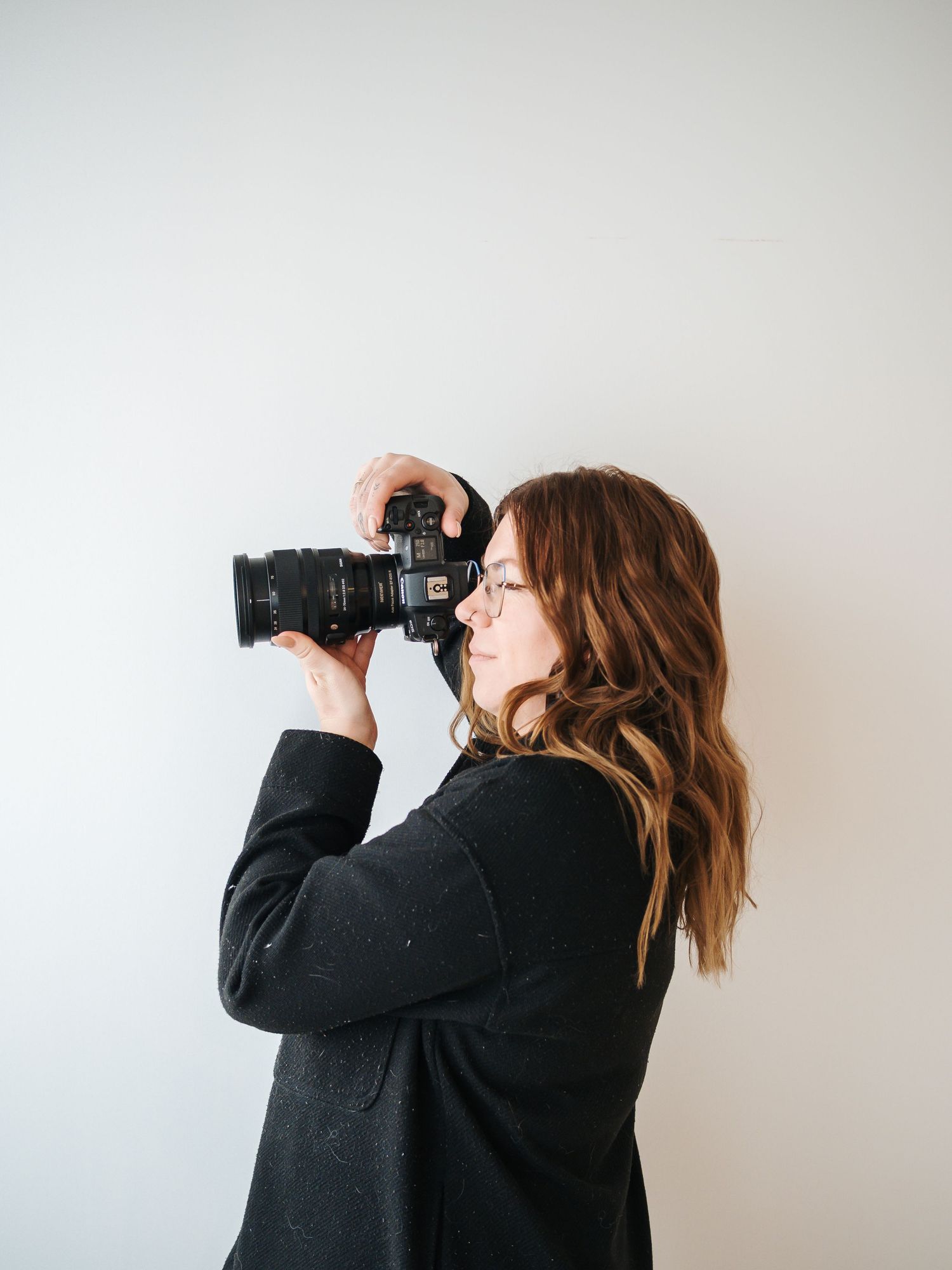 Janice is a wedding and lifestyle photographer near Edmonton. Headshots of photographer holding a camera in St.Albert photography studio