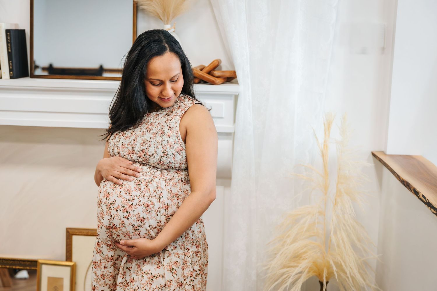 maternity photo session in Edmonton studio. spruce grove mom and baby groups. pregnant mom holds belly in long flower dress