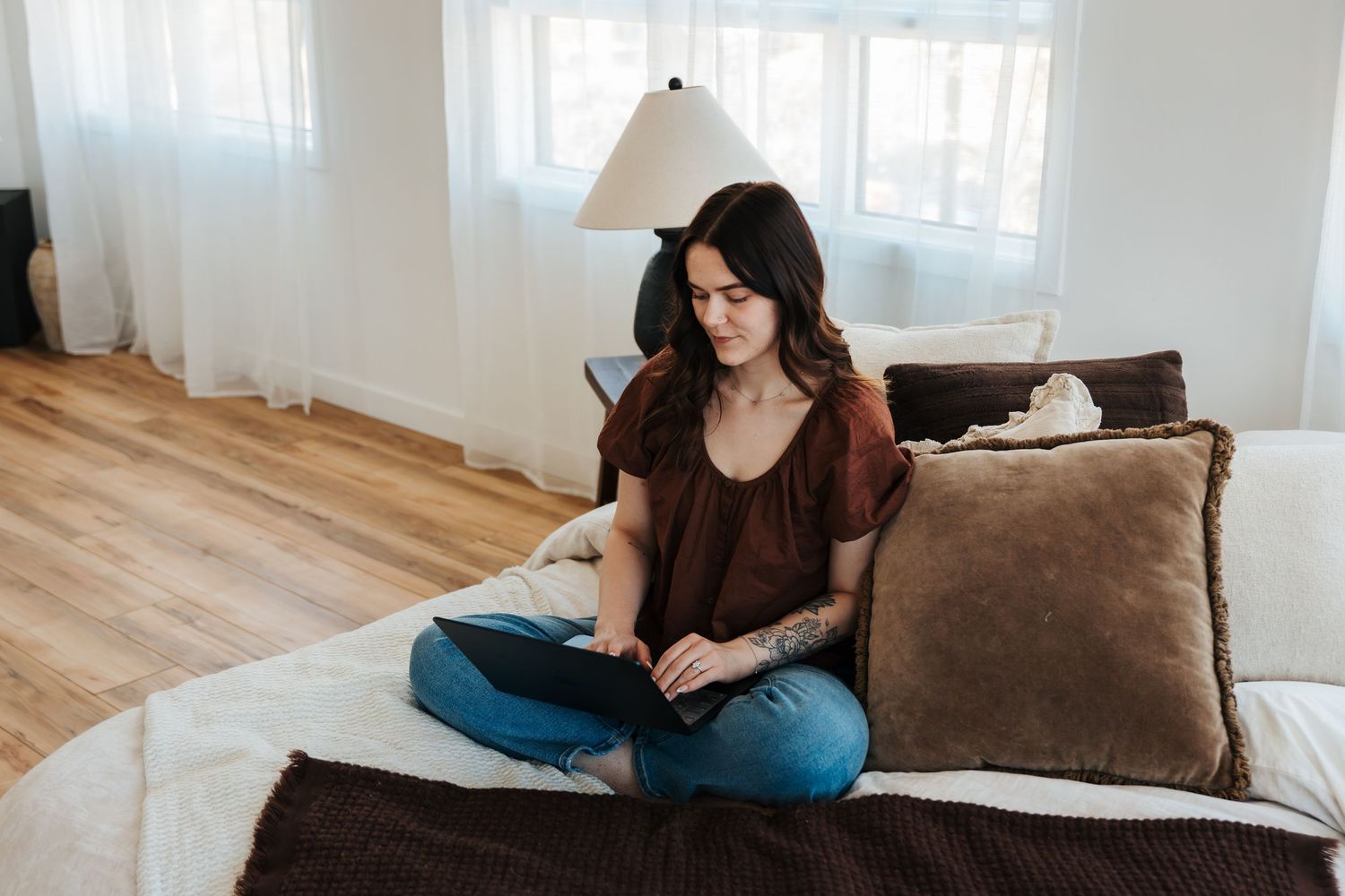 photography classes and styled sessions. female sits on bed with lap top during branding photography session. onoway photographers