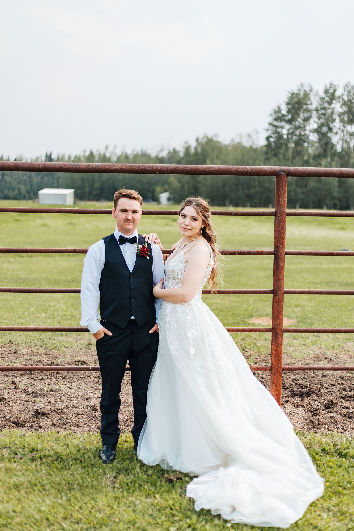 country western wedding pictures, calgary wedding photographers, family photography, bride and groom on farm standing in front of a field