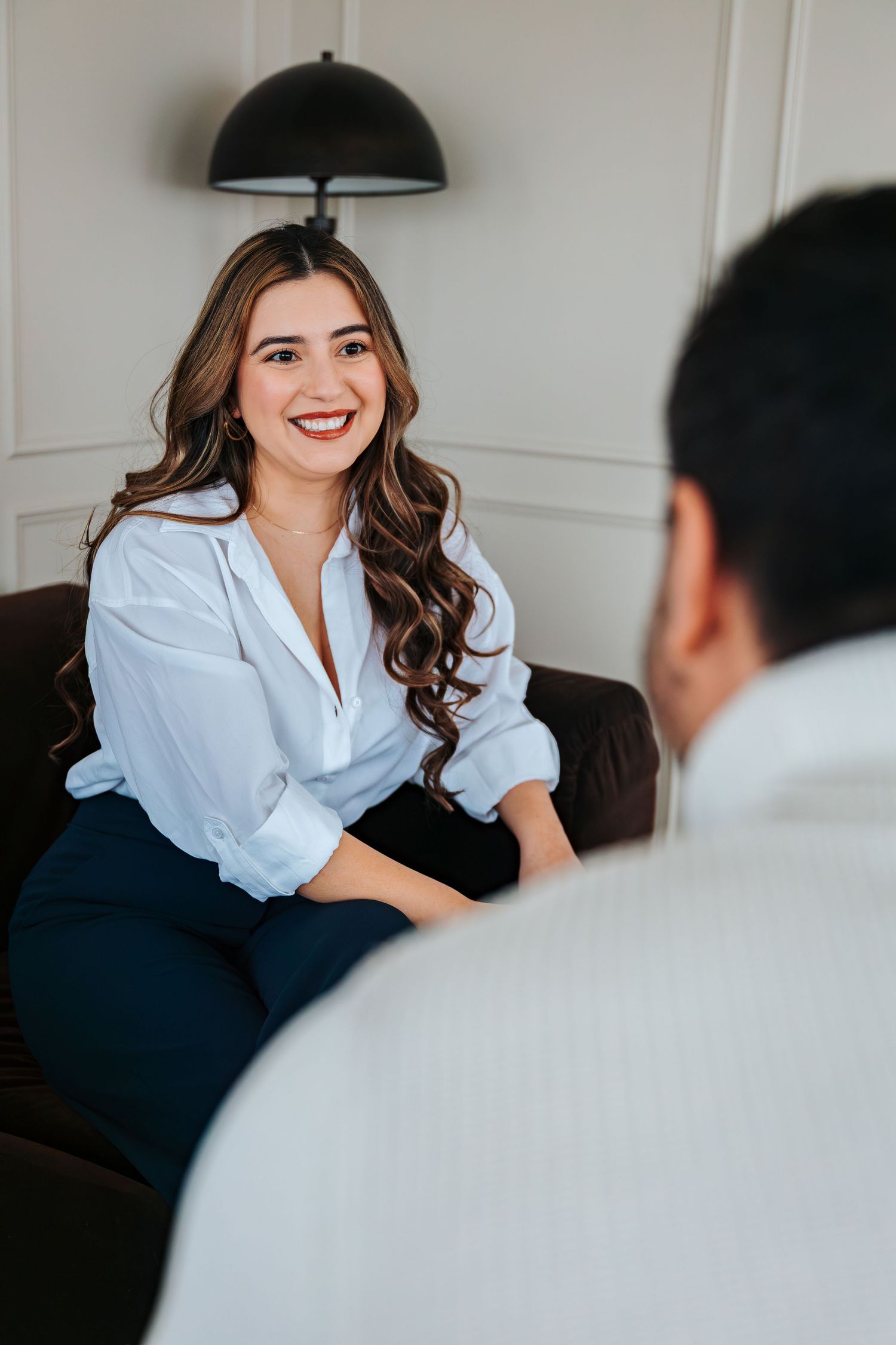 Smiling woman in white blouse sits on dark sofa during a professional meeting or job interview in a modern office. St.Albert photographers