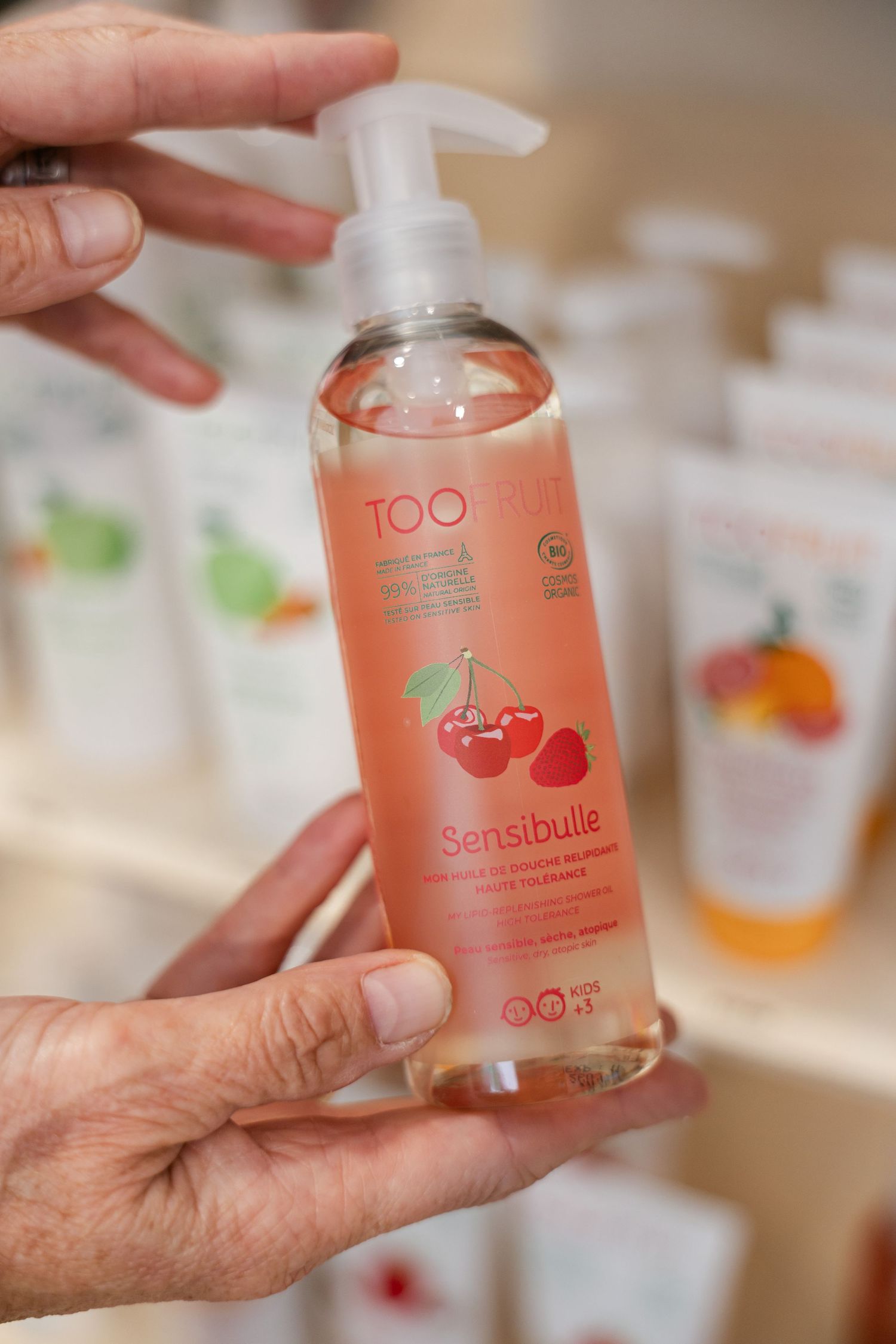 Hands holding TOO organic Sensibulle cherry raspberry facial cleansing gel pump bottle.