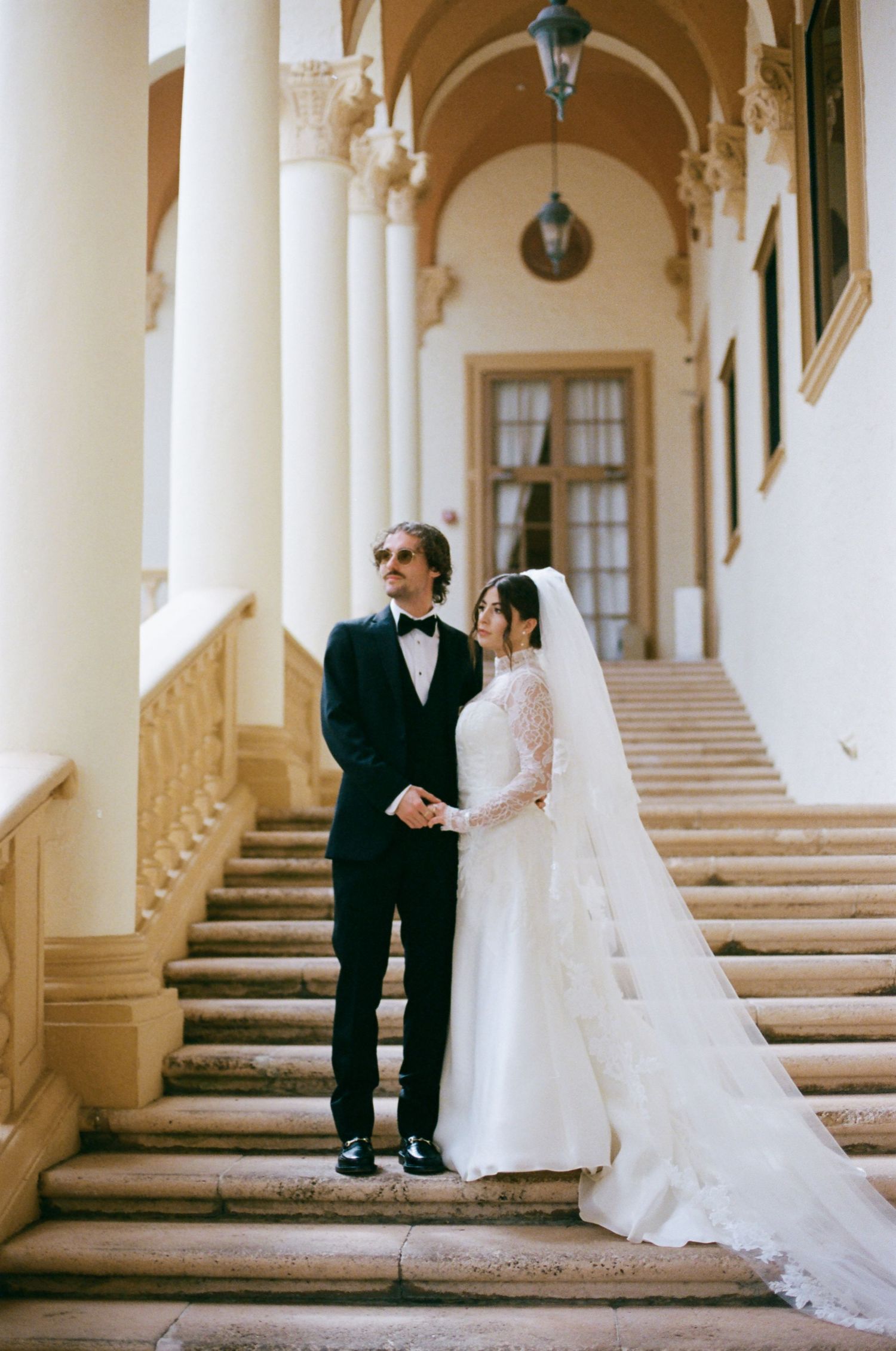 A romantic wedding photo series showing a couple in formal attire posing along an elegant arched hallway.