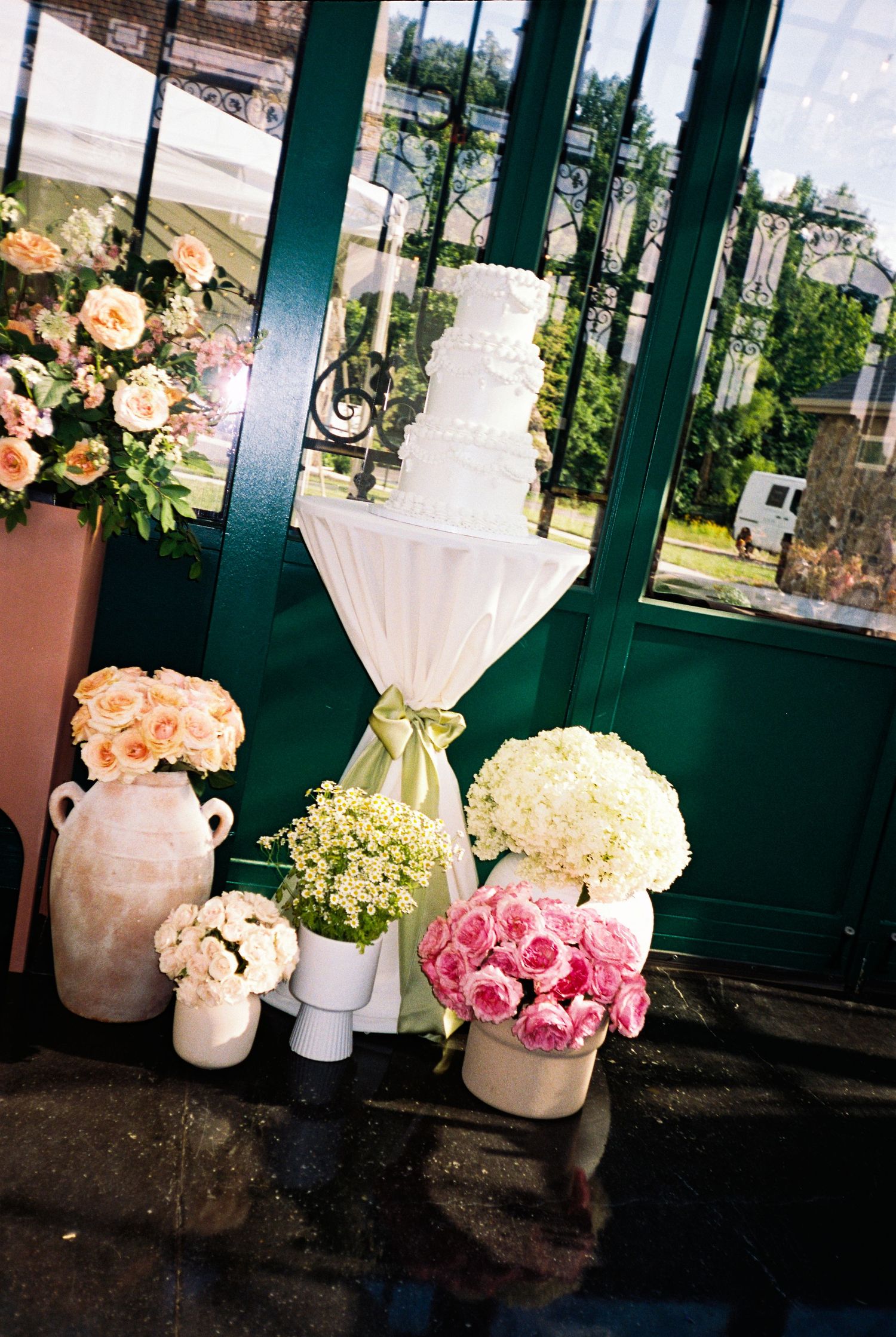 Elegant floral arrangements featuring pink and white roses in ceramic vases displayed against a dark green backdrop.