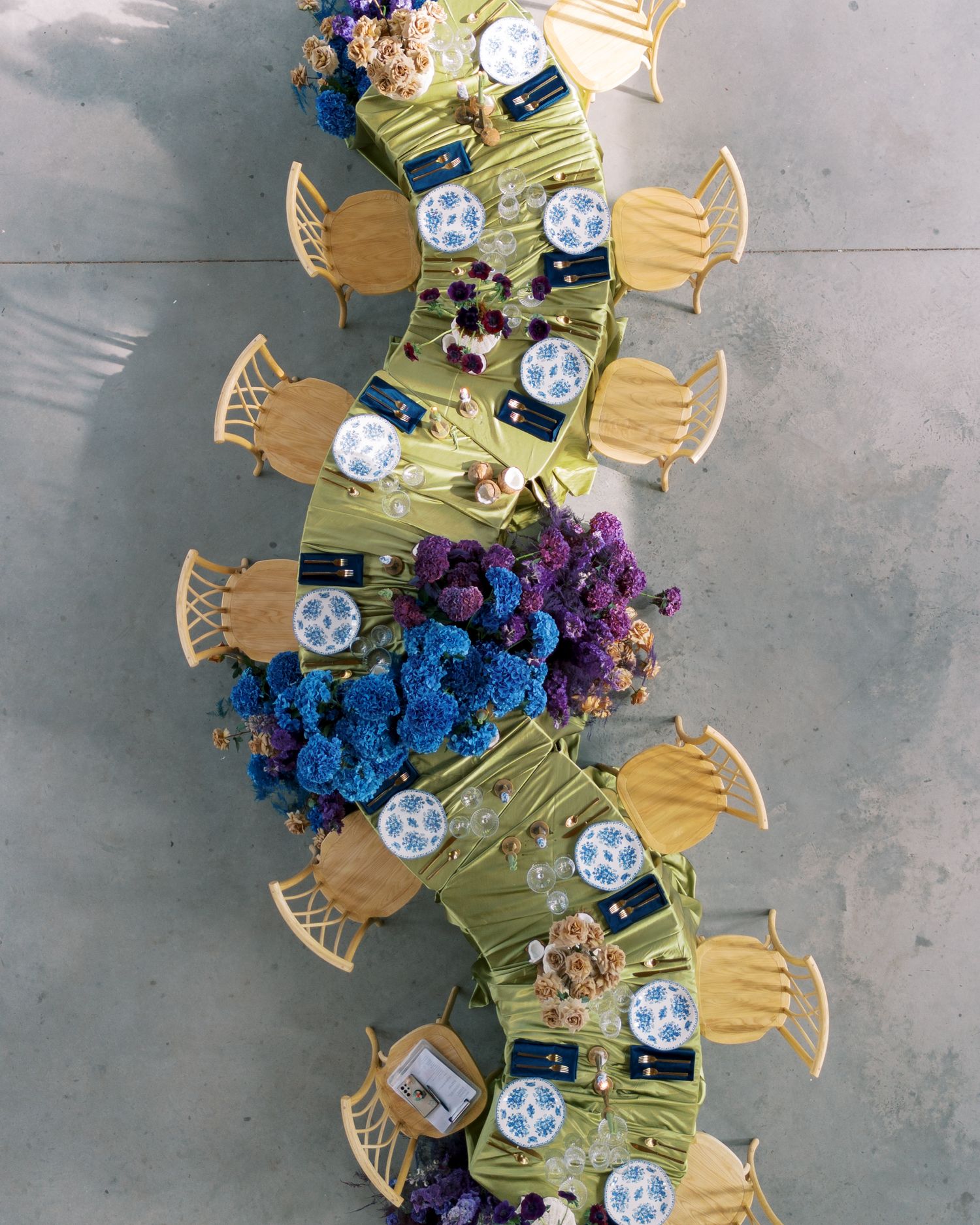 Overhead view of circular dining tables with yellow chairs and blue and purple floral centerpieces in a banquet setup.