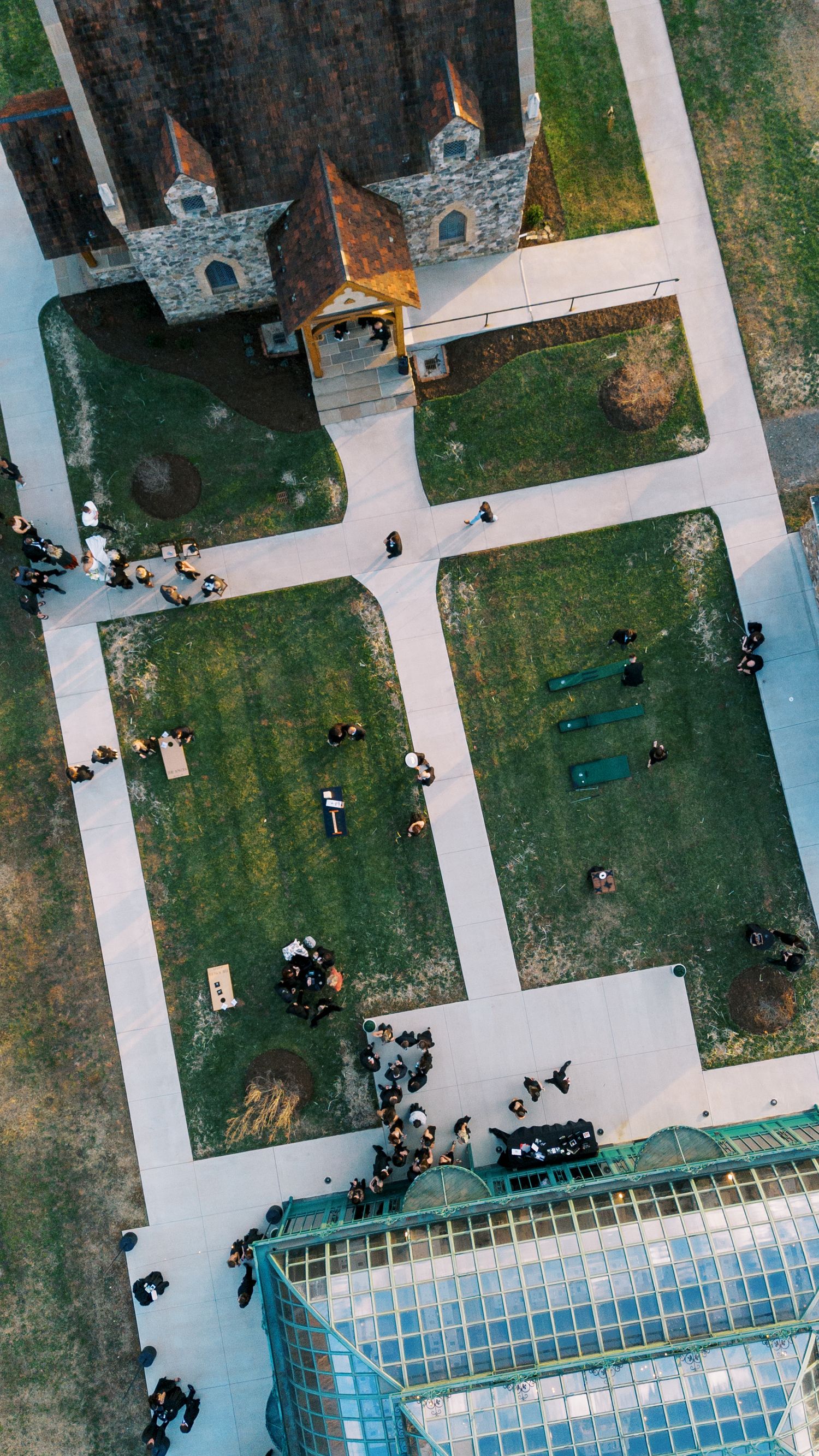 Aerial view of people scattered across a university campus with concrete paths and a glass-roofed building.