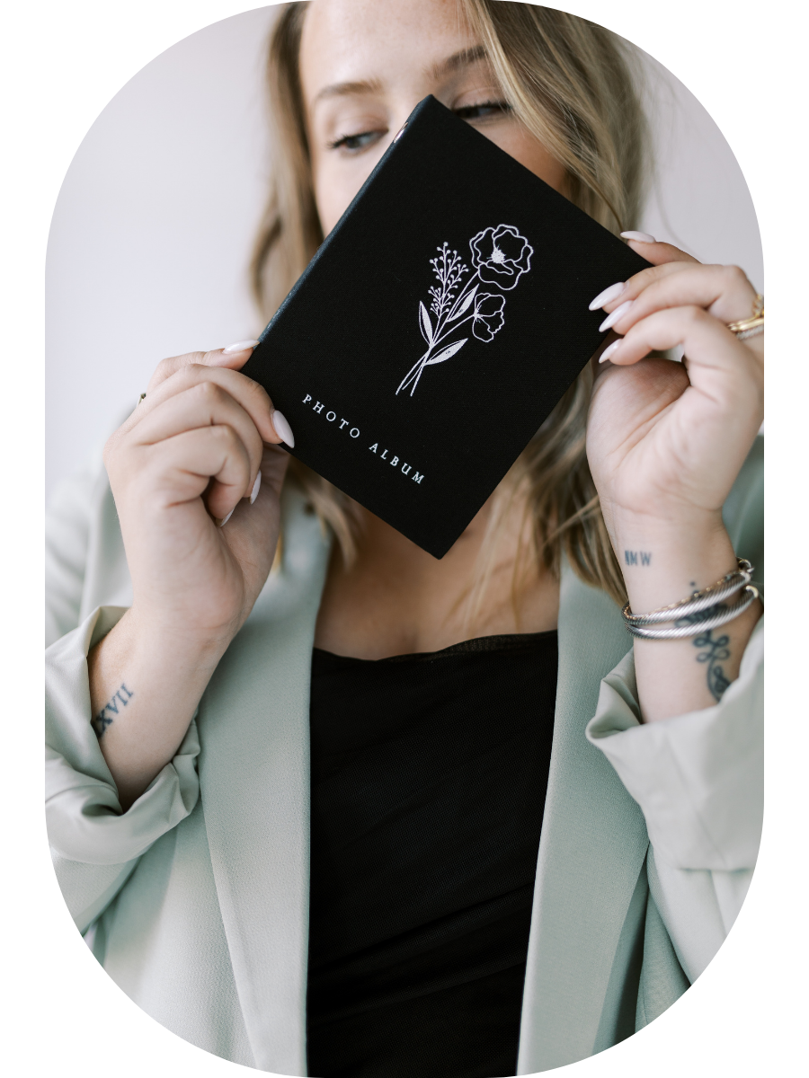Person in light blazer holds black business card against white background showing elegant brand identity mockup.