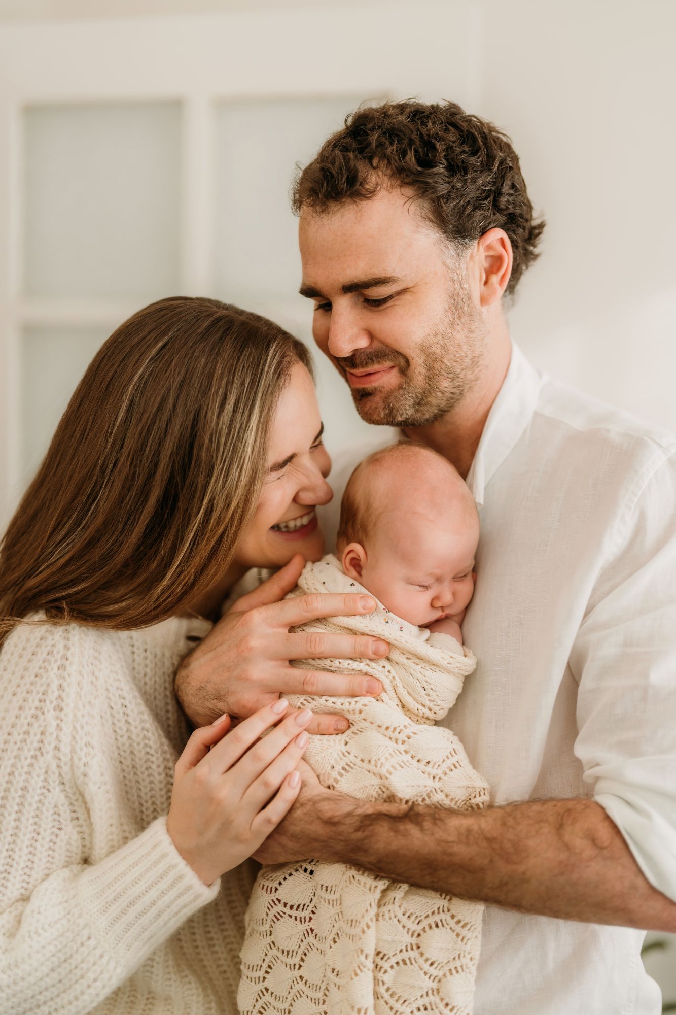 Parents cuddling their new baby during a relaxed home session