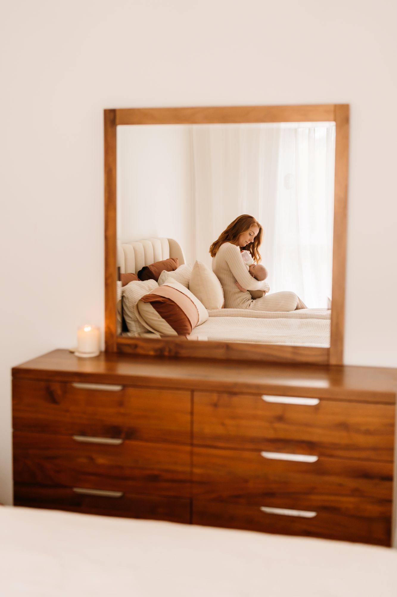 Mother holding her newborn reflected in a mirror during an in-home newborn photography session