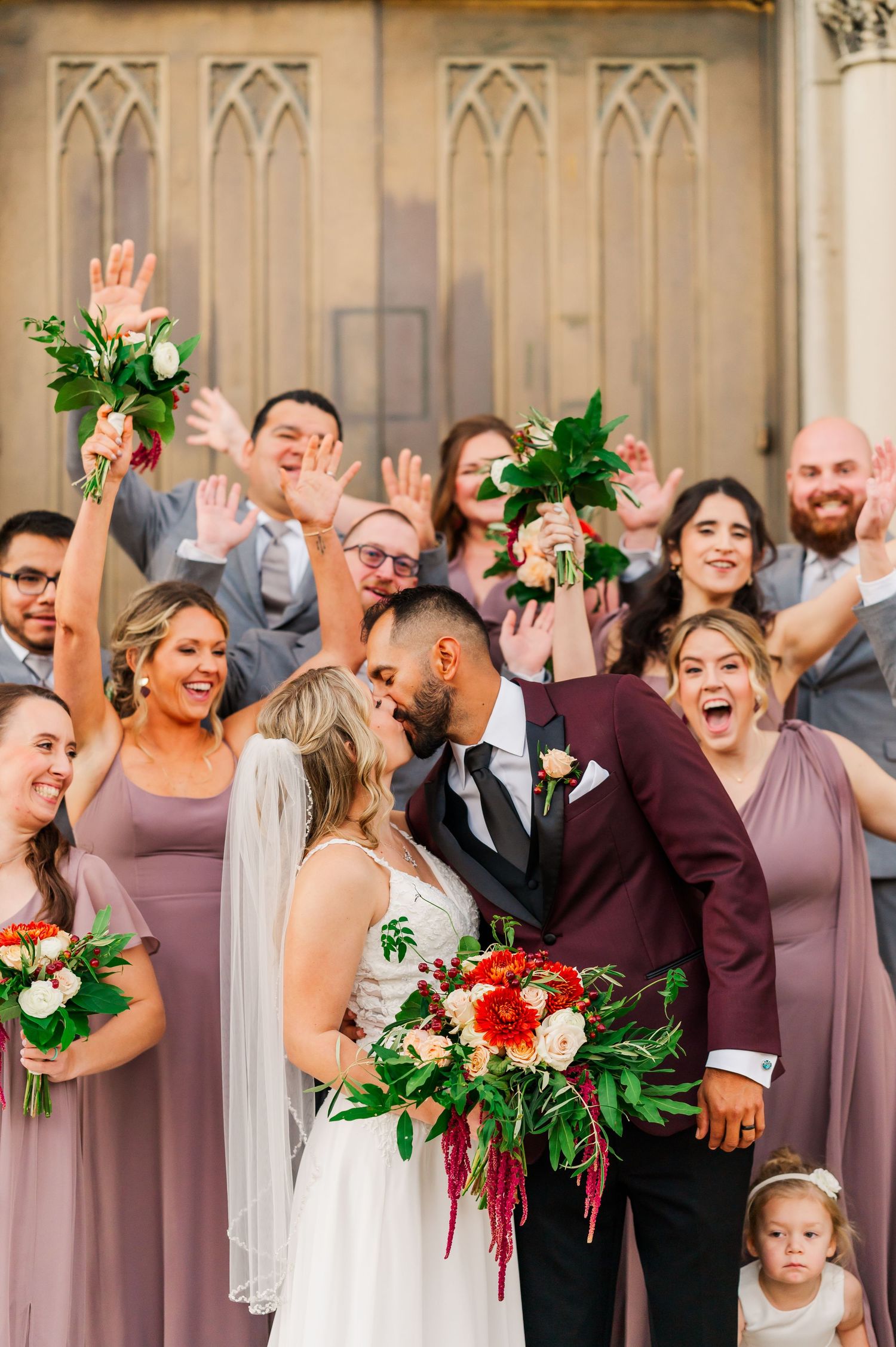 Bride and Groom kissing in front of bridal party cheering on wedding day