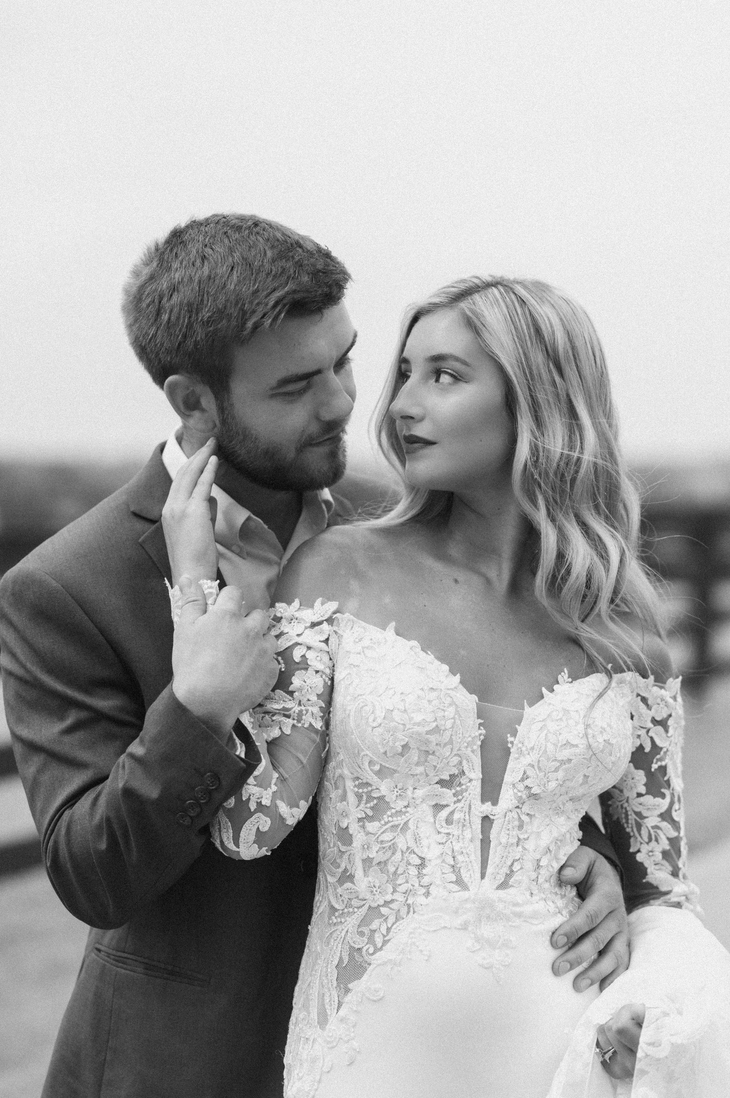 Black and white shot with bride in front of groom reaching back over her shoulder to pull in face in while looking back at him
