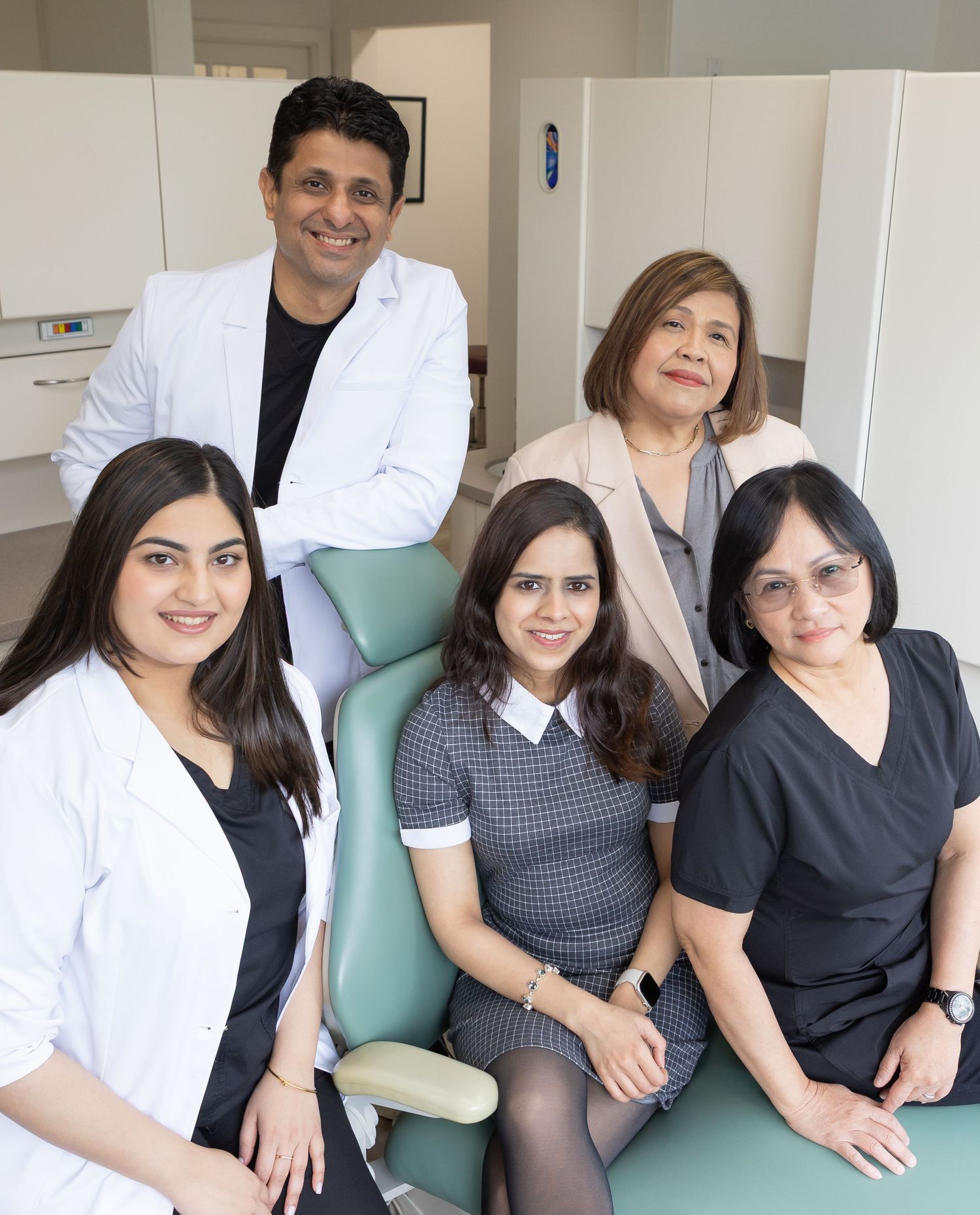 Medical office team poses together in a clinical setting showing professional staff in white coats and scrubs.