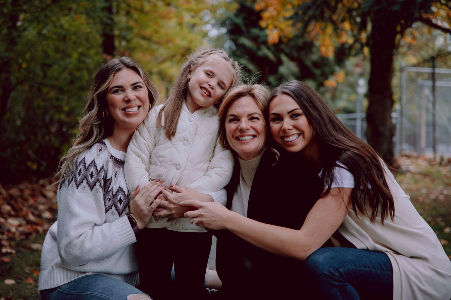 A group shares joyful laughter while embracing during an autumn outdoor photo session.