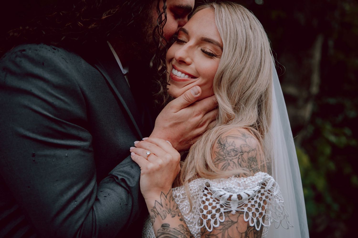 Intimate wedding portrait showing tender romantic moment with lace dress detail.