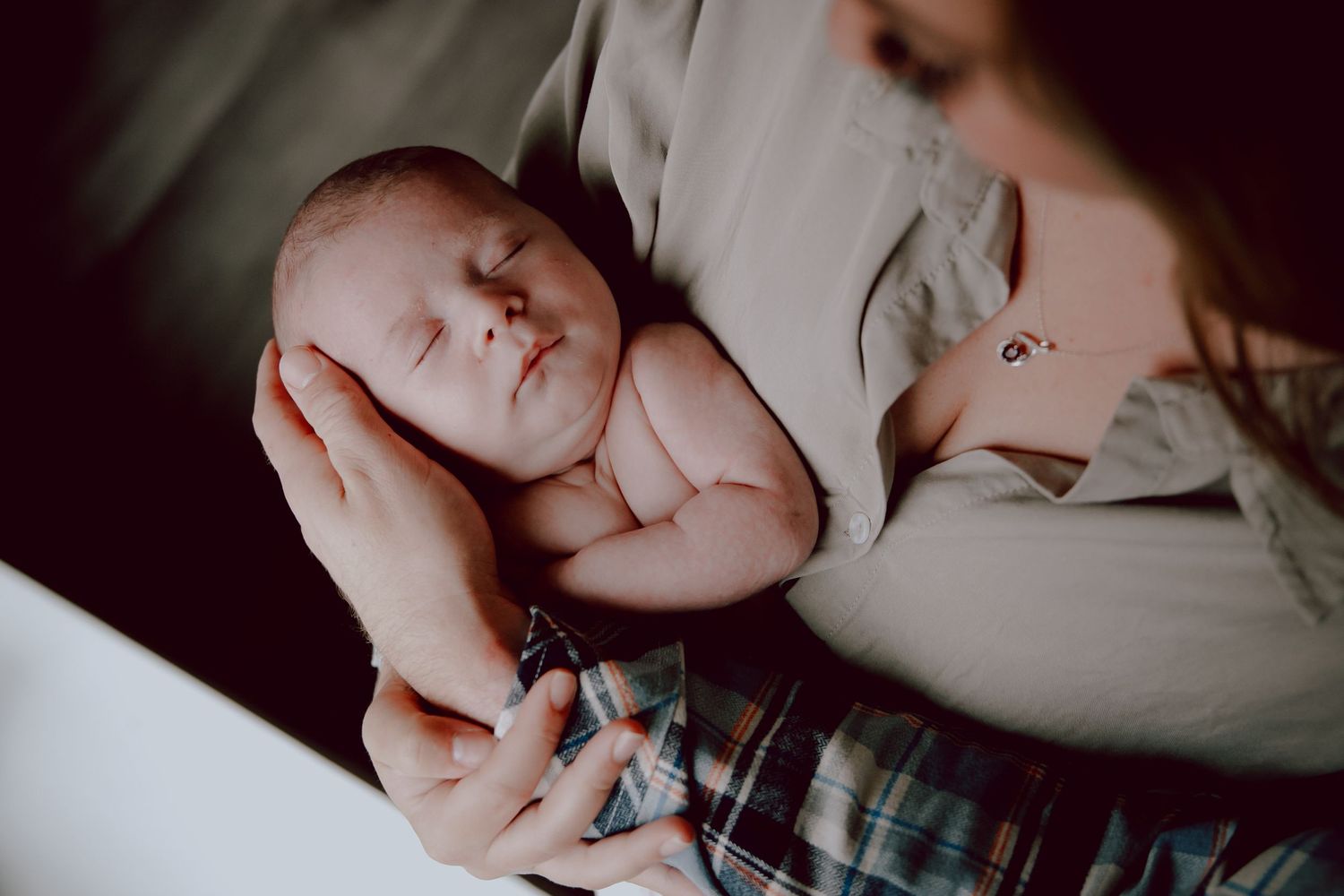 Peaceful newborn baby sleeping while being cradled in loving arms.