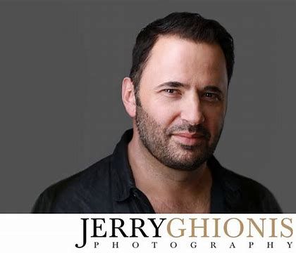 Professional studio portrait shot of someone wearing a black shirt against a dark background with a watermark.