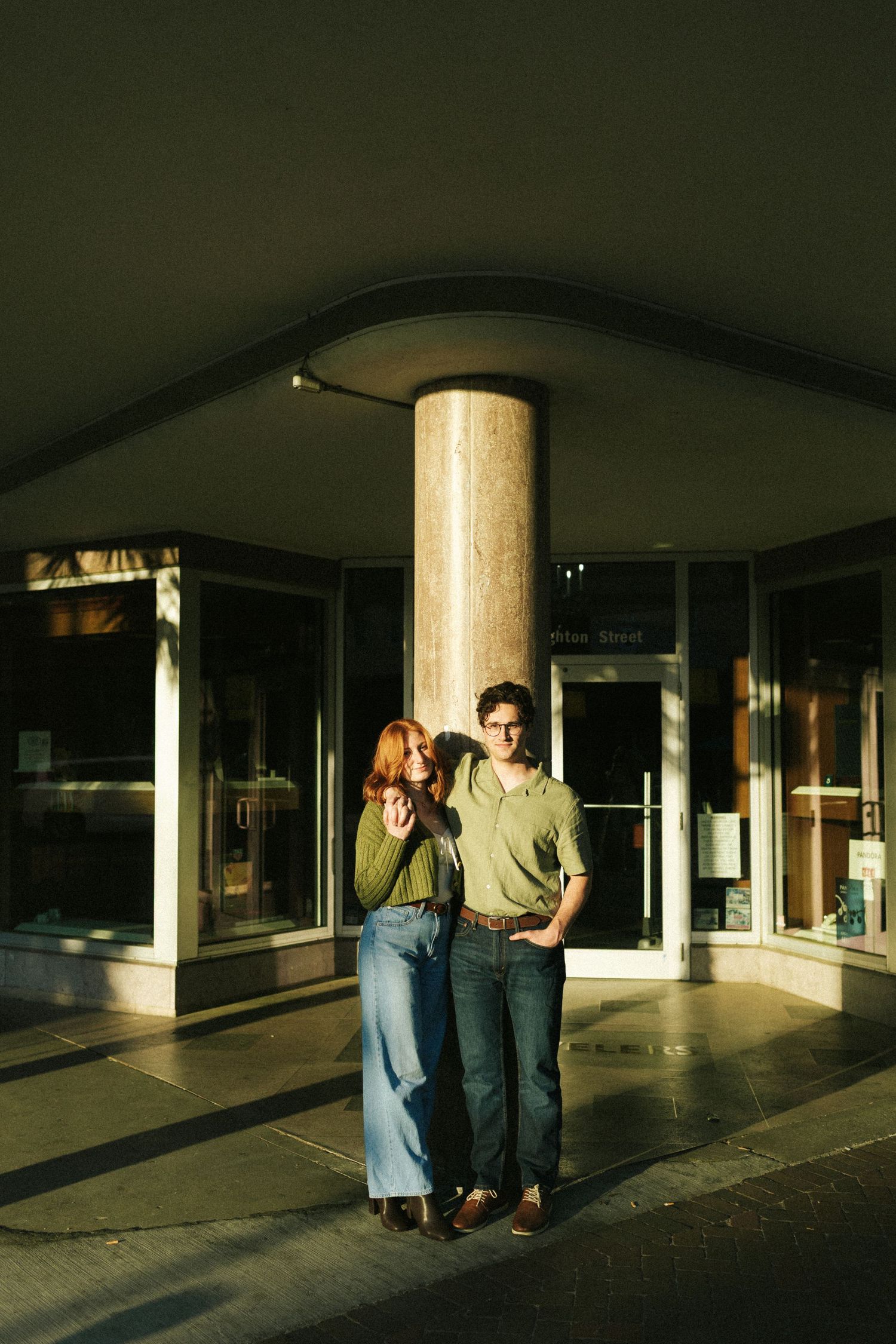 A couple leans against a pole on Broughton Street in Savannah, arms wrapped around each other