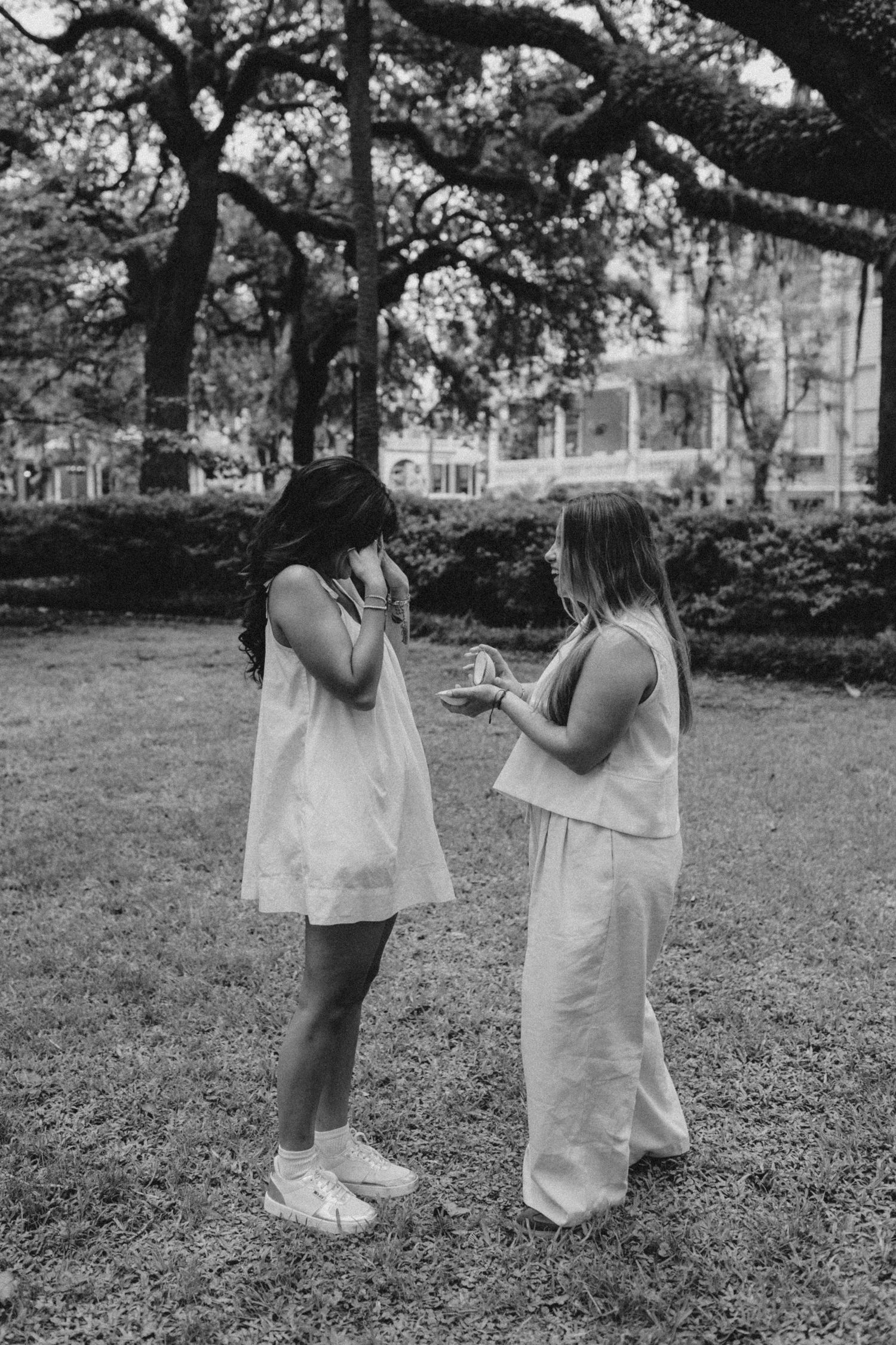 A woman covers her face in excitement as her girlfriend proposes in Forsyth Park