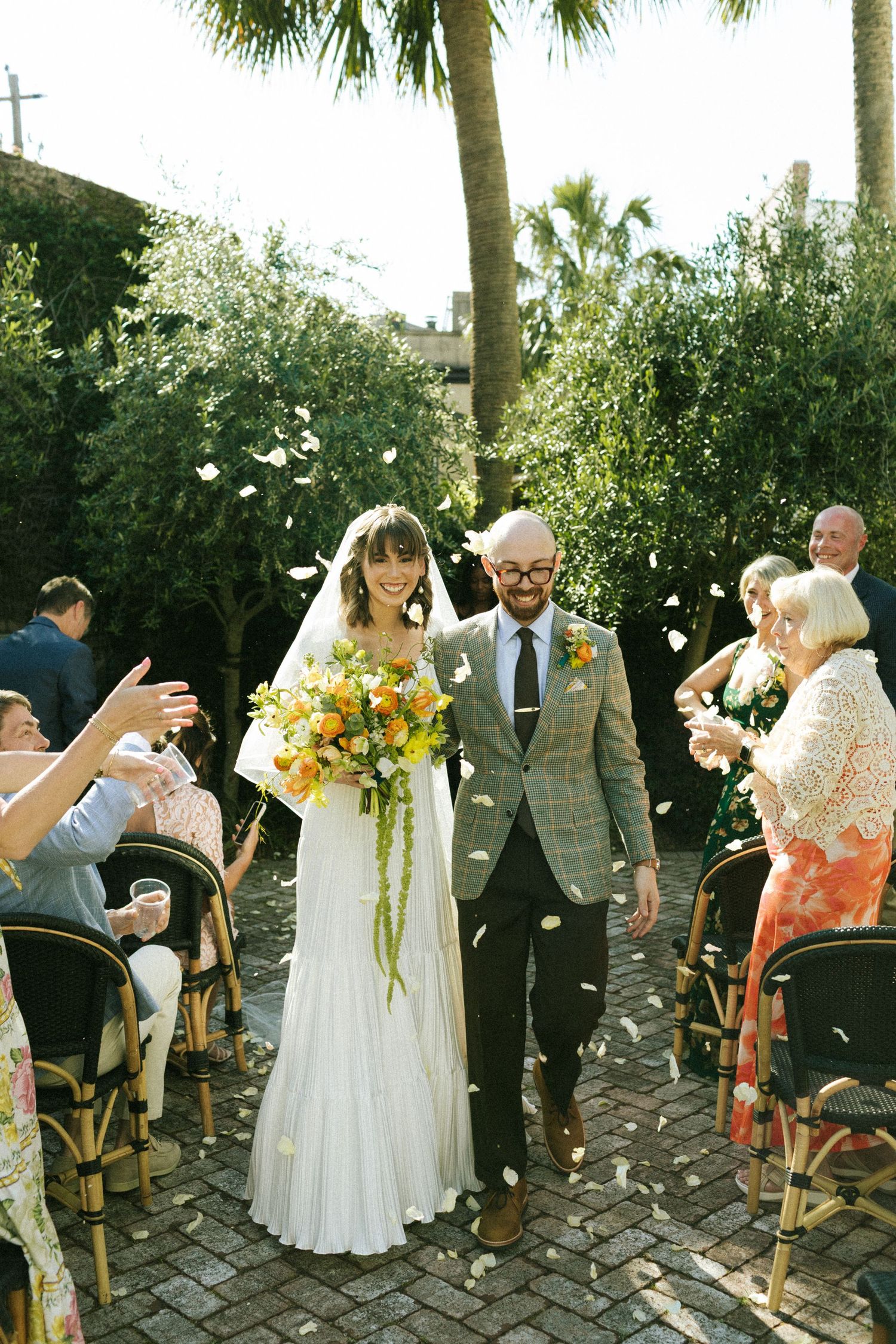 A couple walks back down the aisle at the end of their wedding ceremony at the Bellwether Inn. Flower petals are being thrown over them