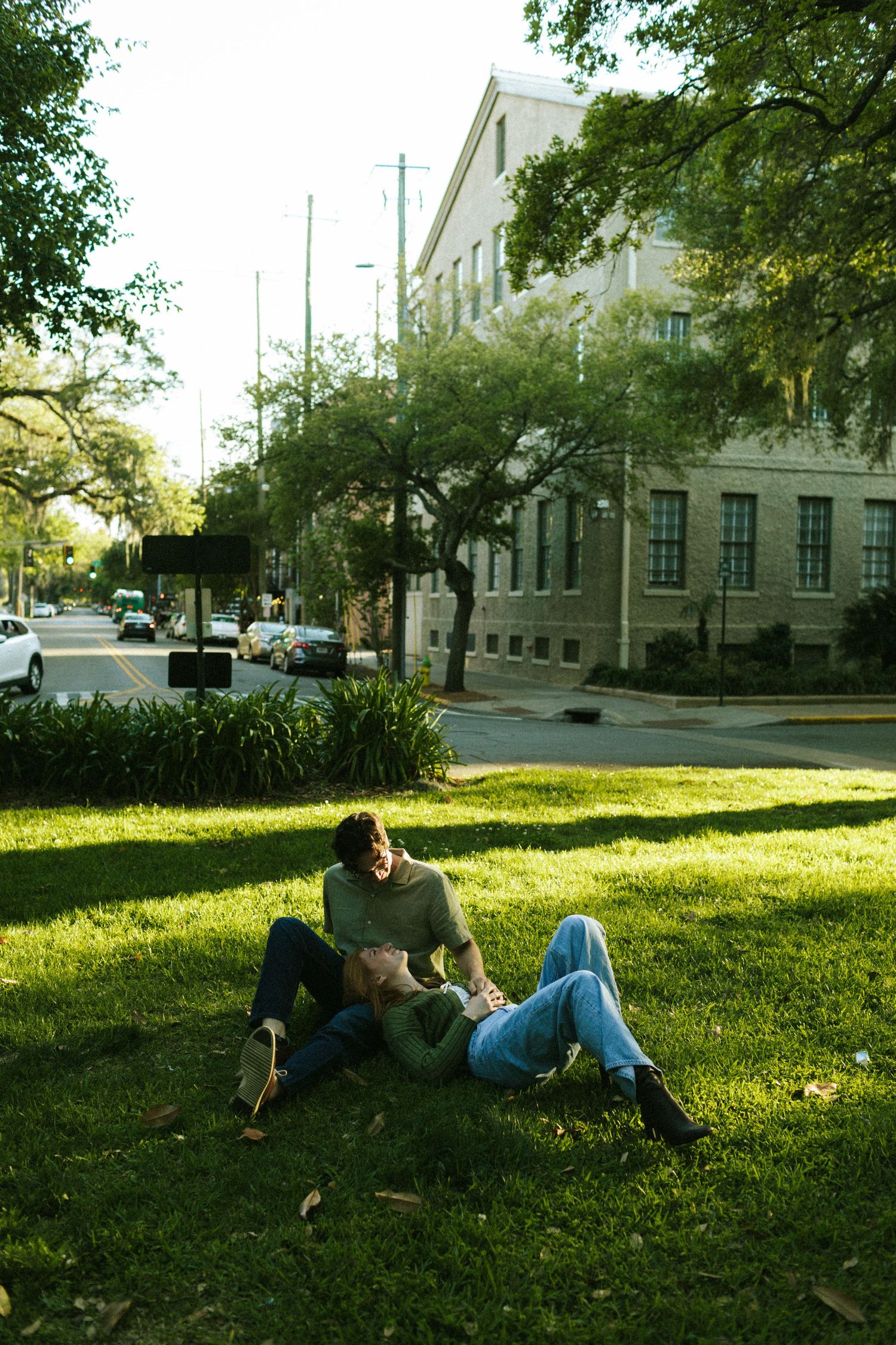 A woman lies in her fiancé's lap, looking up at him in a square in downtown Savannah, Georgia
