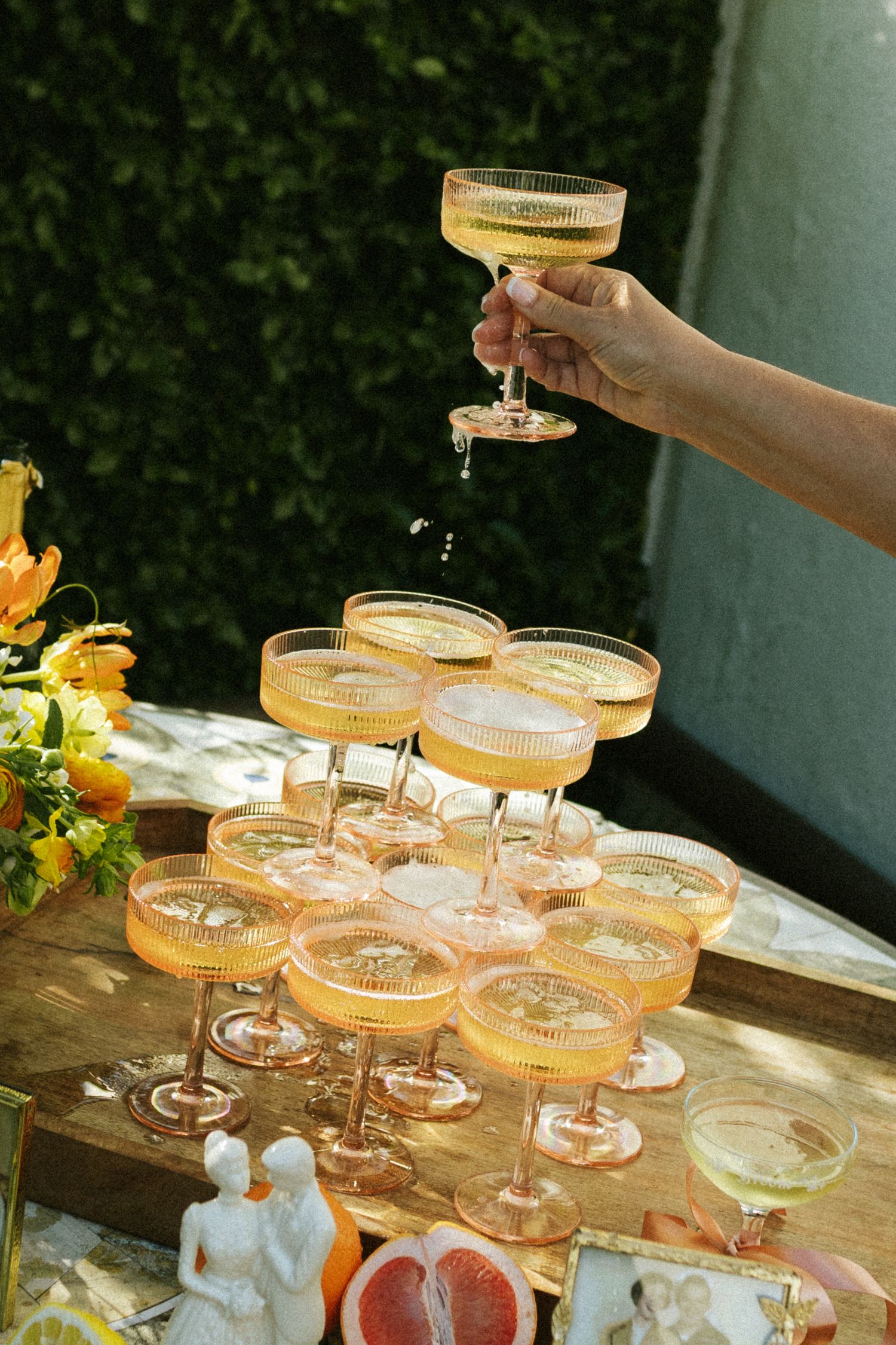 A hand grabs the flute of champagne off the top of a champagne tower