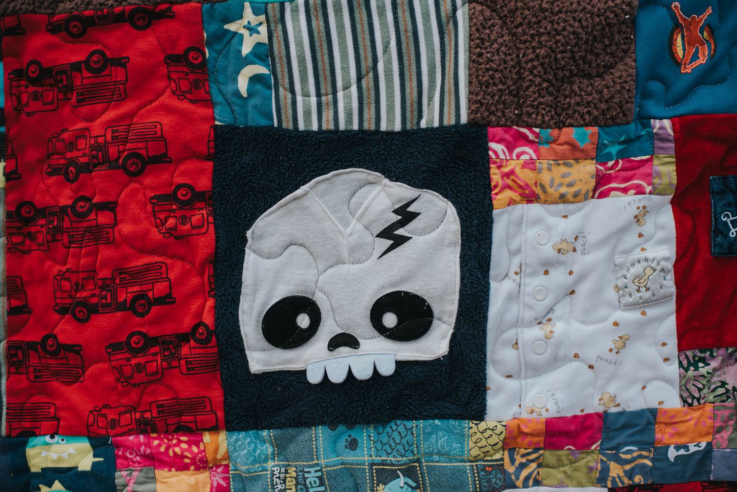 A portion of a patchwork memory quilt showing a square with a funny looking skeleton face.