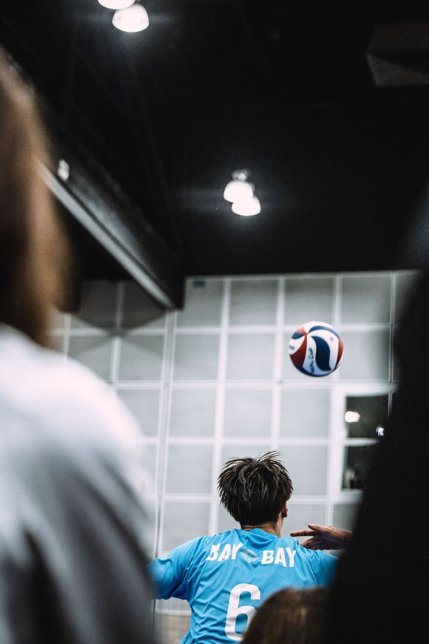 Player wearing blue jersey number 6 sets a volleyball during an indoor game.