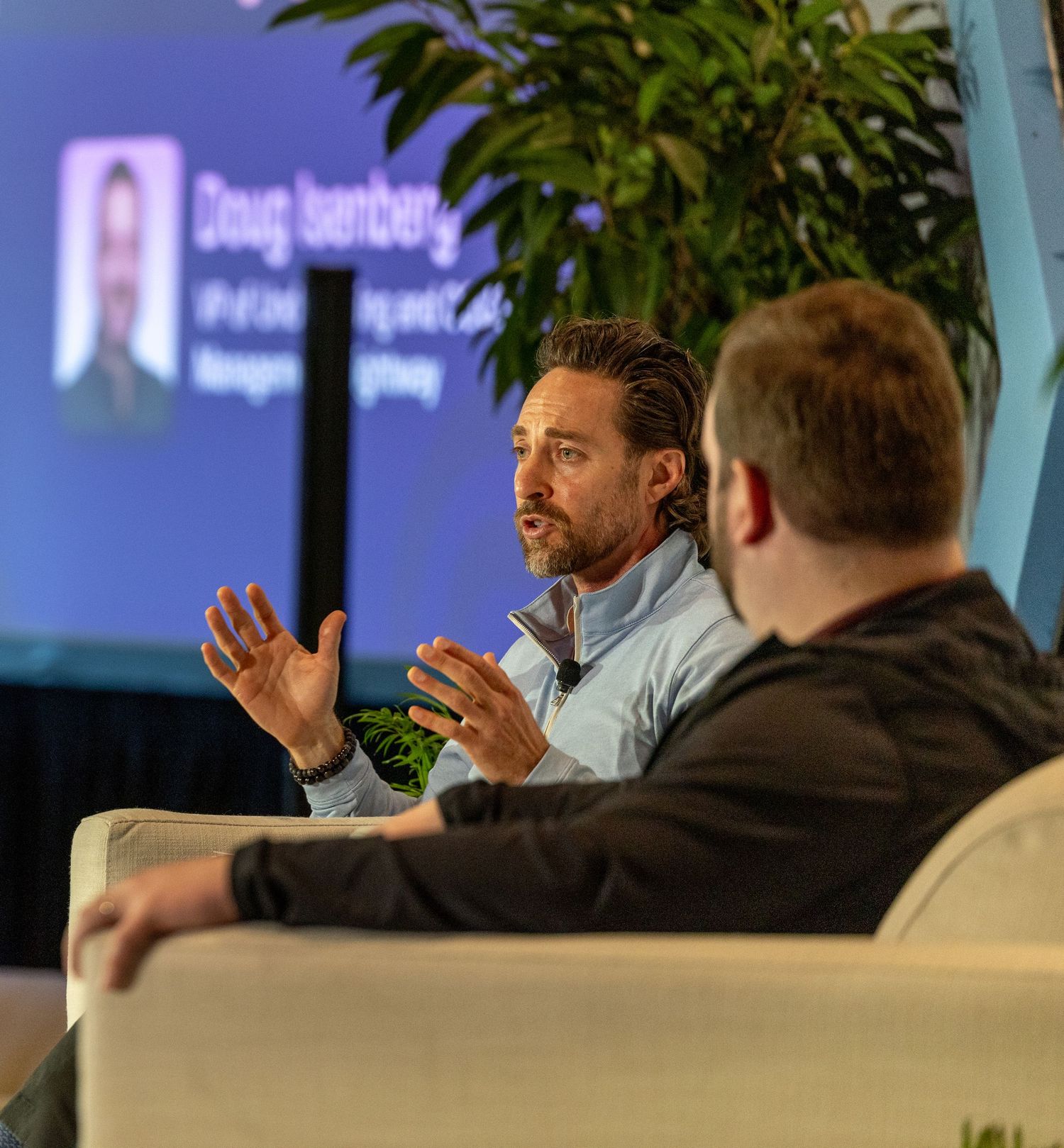 Doug Isenberg speaks on stage at a professional conference panel discussion with another attendee seated nearby.