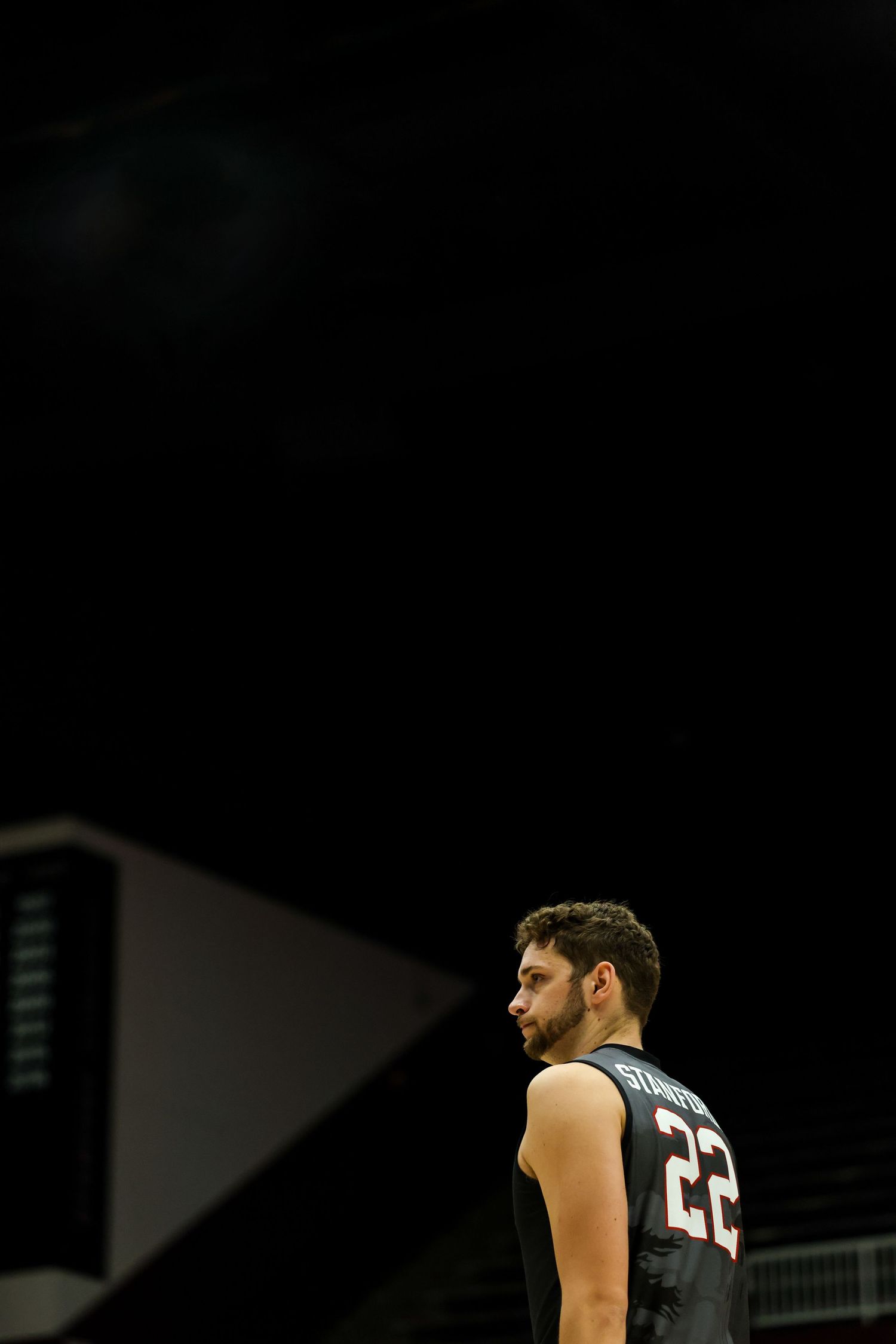 Basketball player wearing jersey number 22 stands on a dimly lit court during a game.