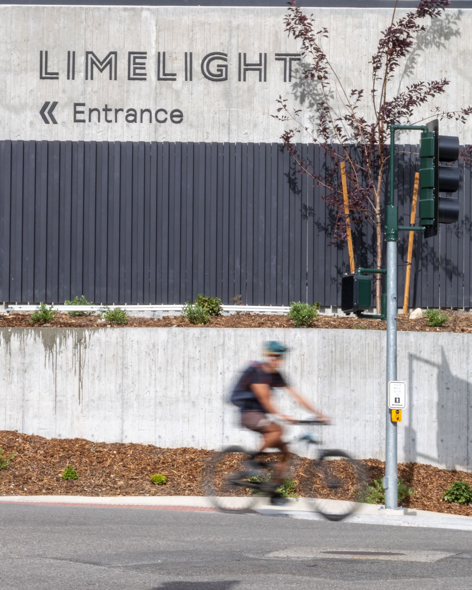 A cyclist passes the Limelight hotel entrance sign on a sunny day.