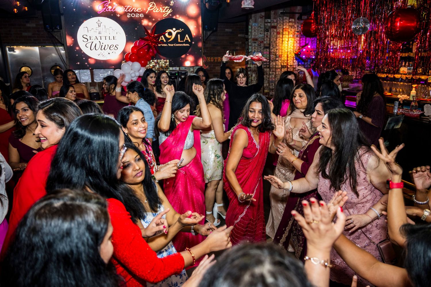 Lively Indian party with women in colorful traditional attire dancing together at a festive celebration.