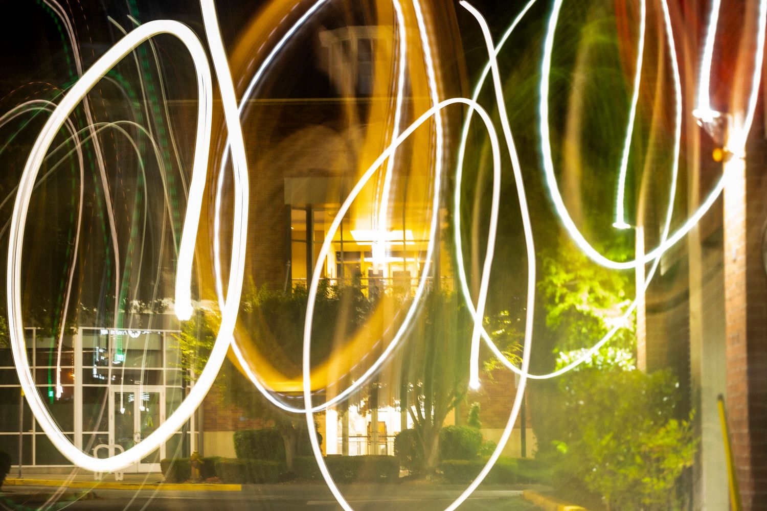 Abstract long exposure light painting photography at night outside a building.