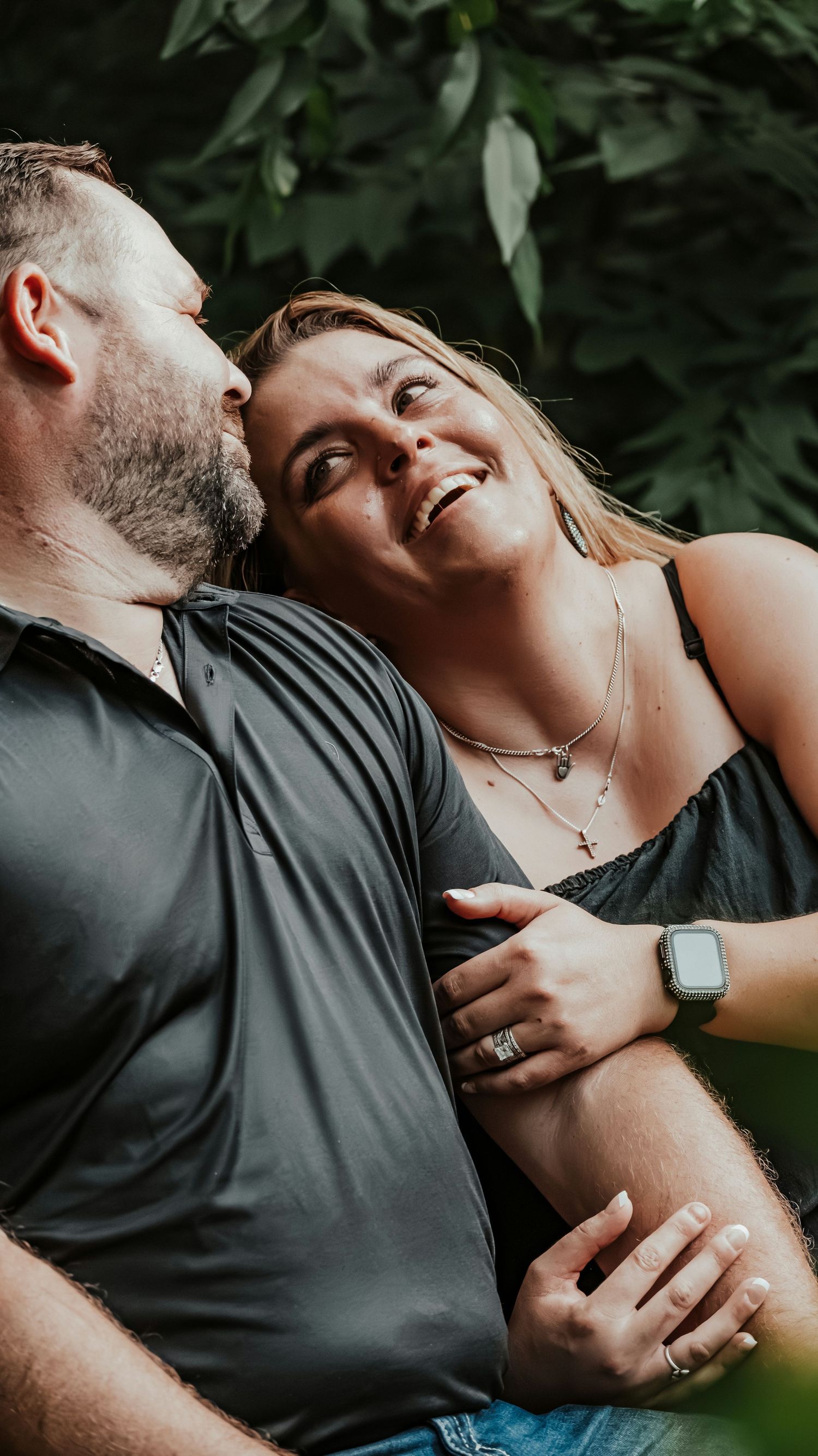 Happy couple sharing a tender moment outdoors, woman smiling as man kisses her cheek.