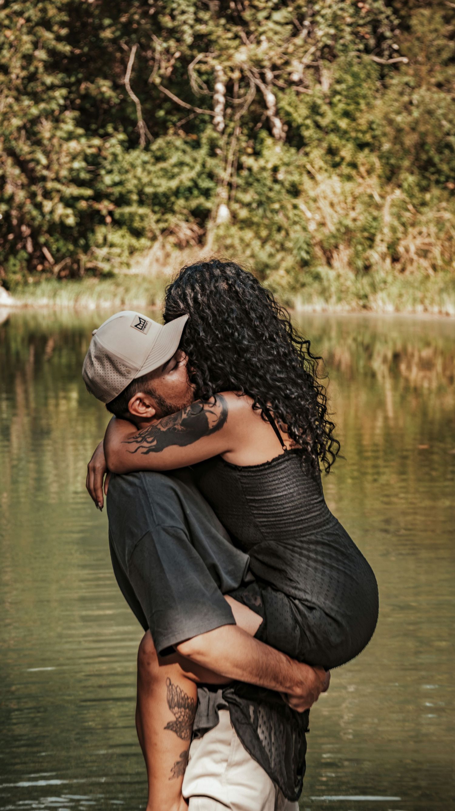 A couple shares a romantic embrace by a serene spring for a couples session.
