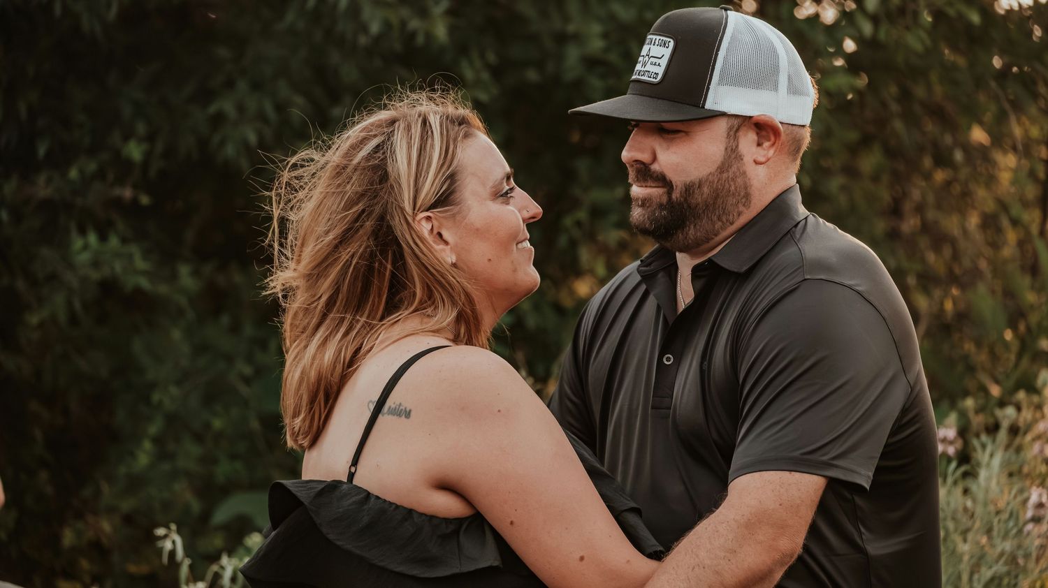 Couple sharing a loving glance while embracing outdoors in warm golden light.