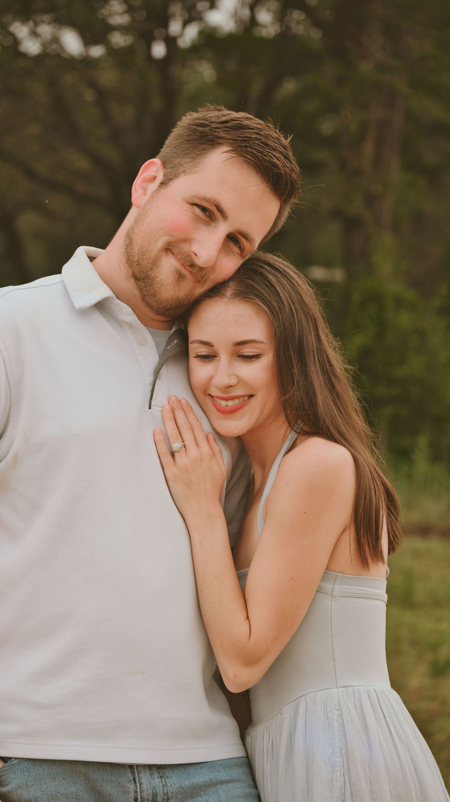 Happy couple in soft evening light, woman leaning on mans shoulder for a family session.