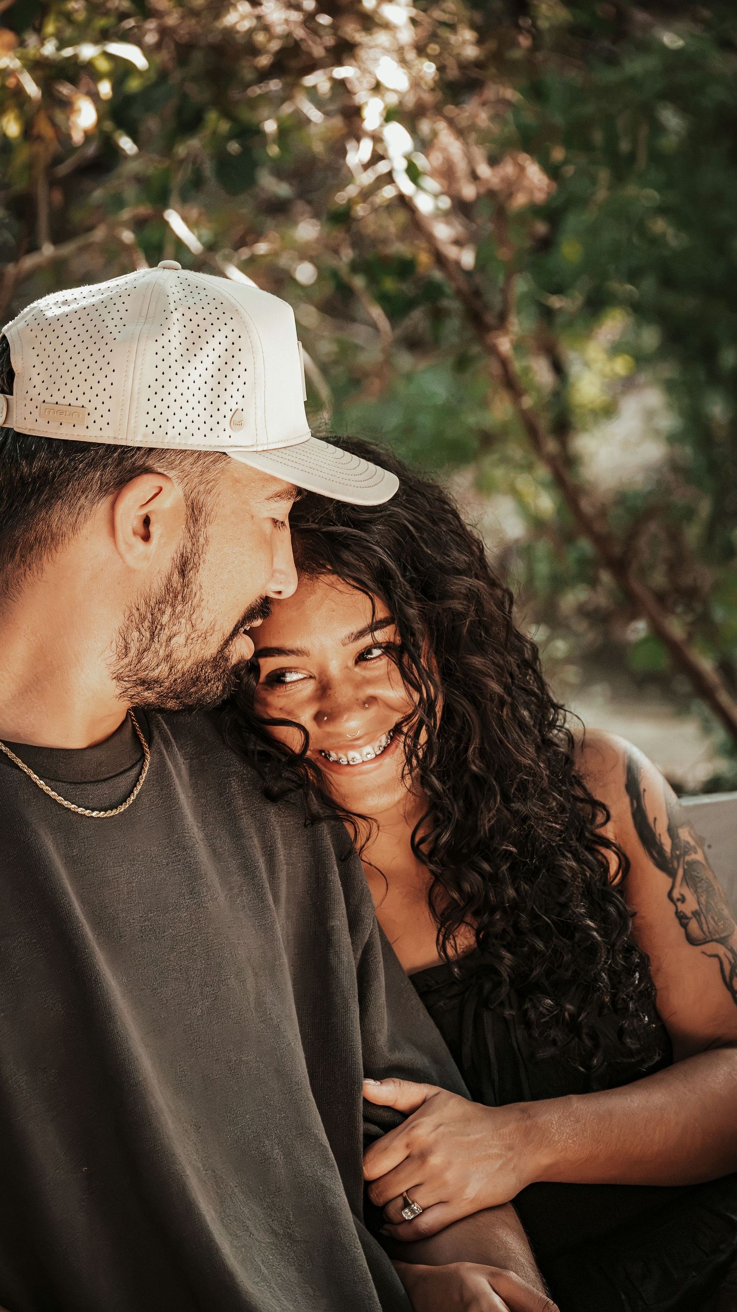 A smiling couple sharing a tender moment outdoors for a couples session.