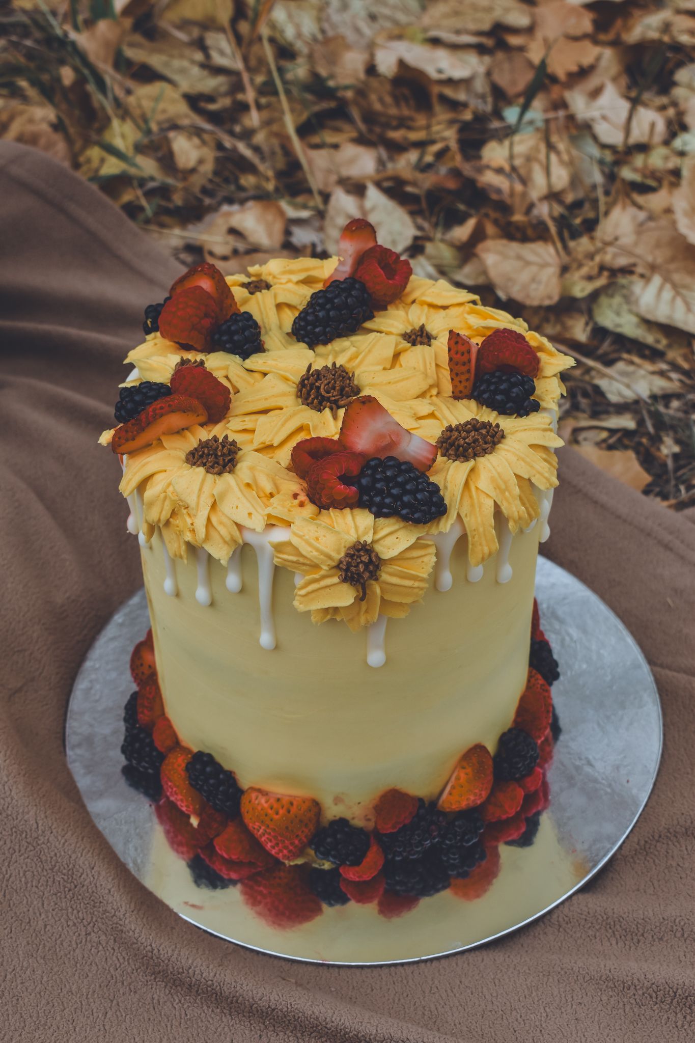 Elegant yellow birthday cake with sunflower frosting, fresh strawberries and blackberries on top. Family Photographer in Pflugerville, Tx