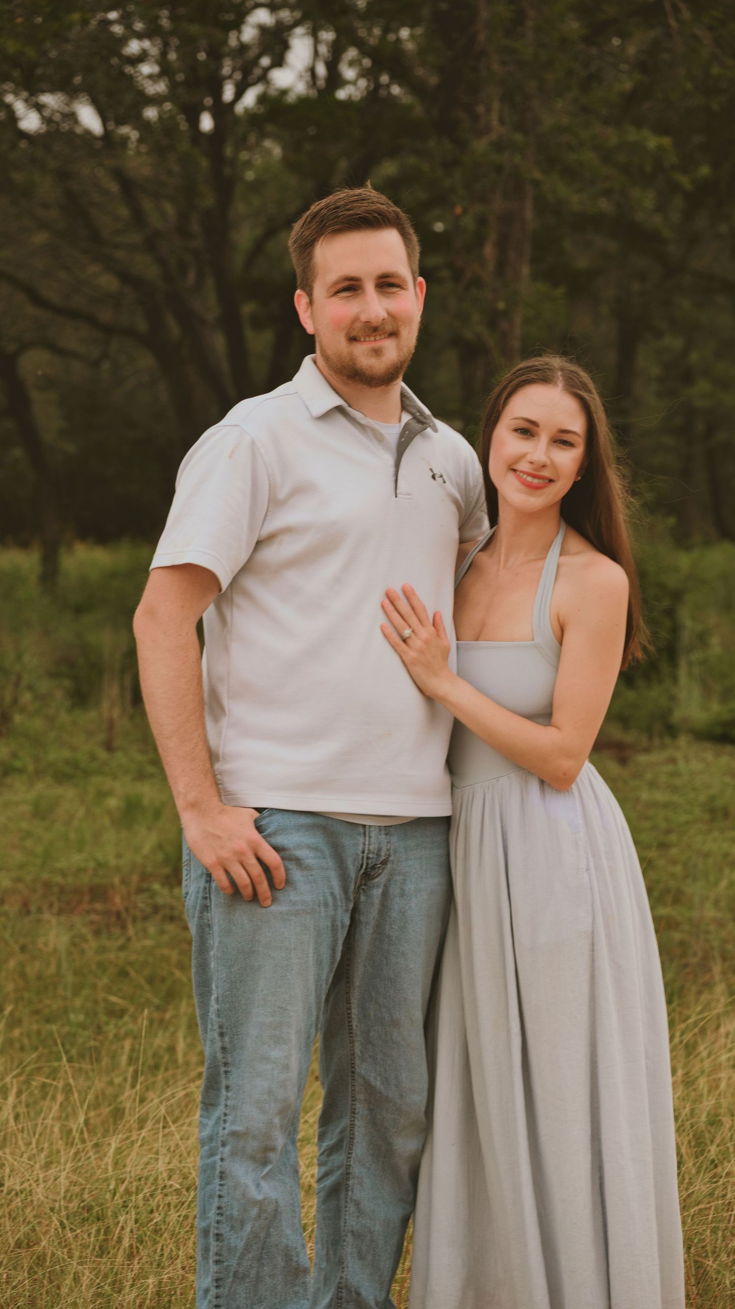 A smiling couple poses outdoor for a family session.