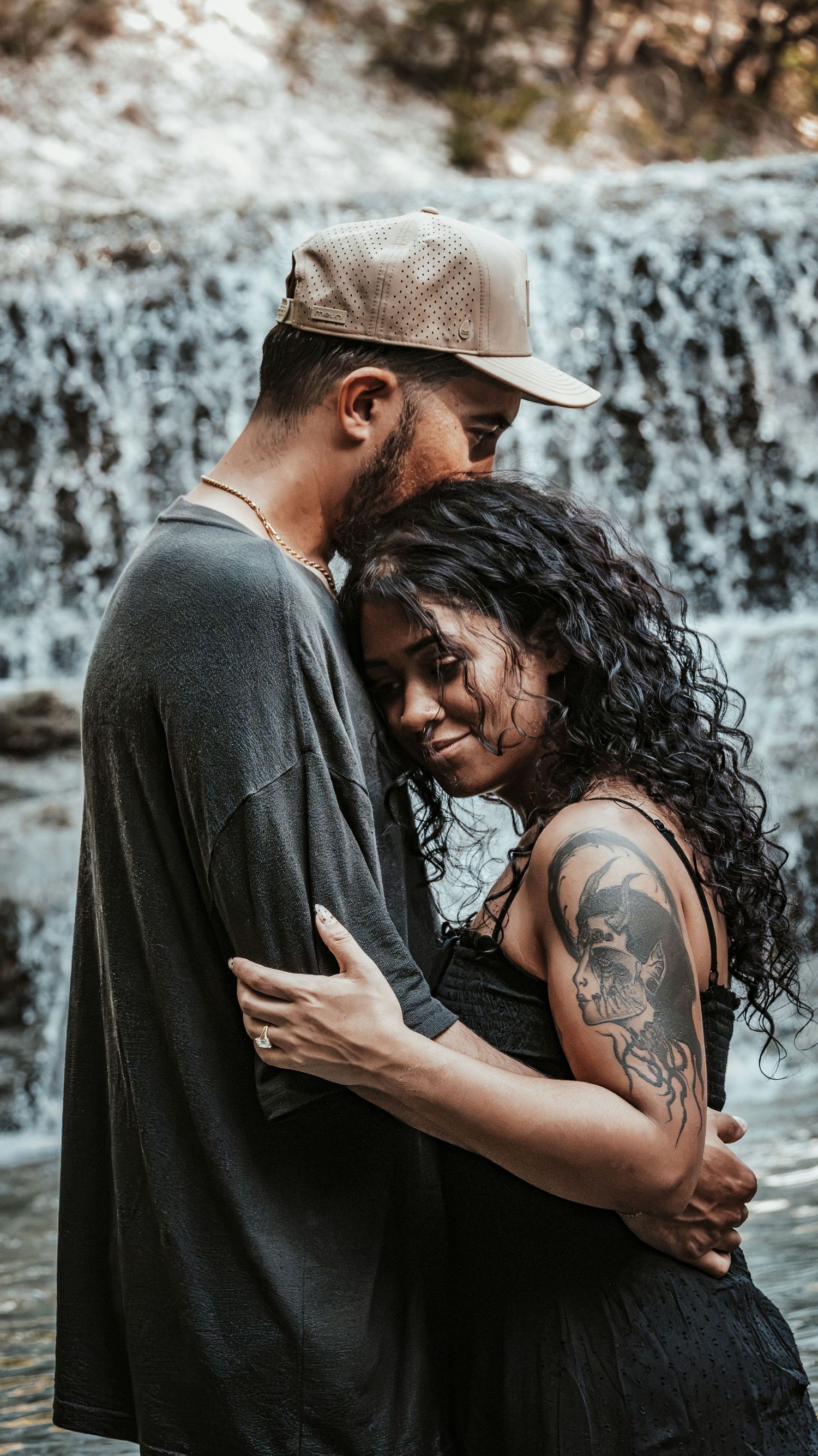 Couple sharing a loving embrace near a beautiful waterfall.