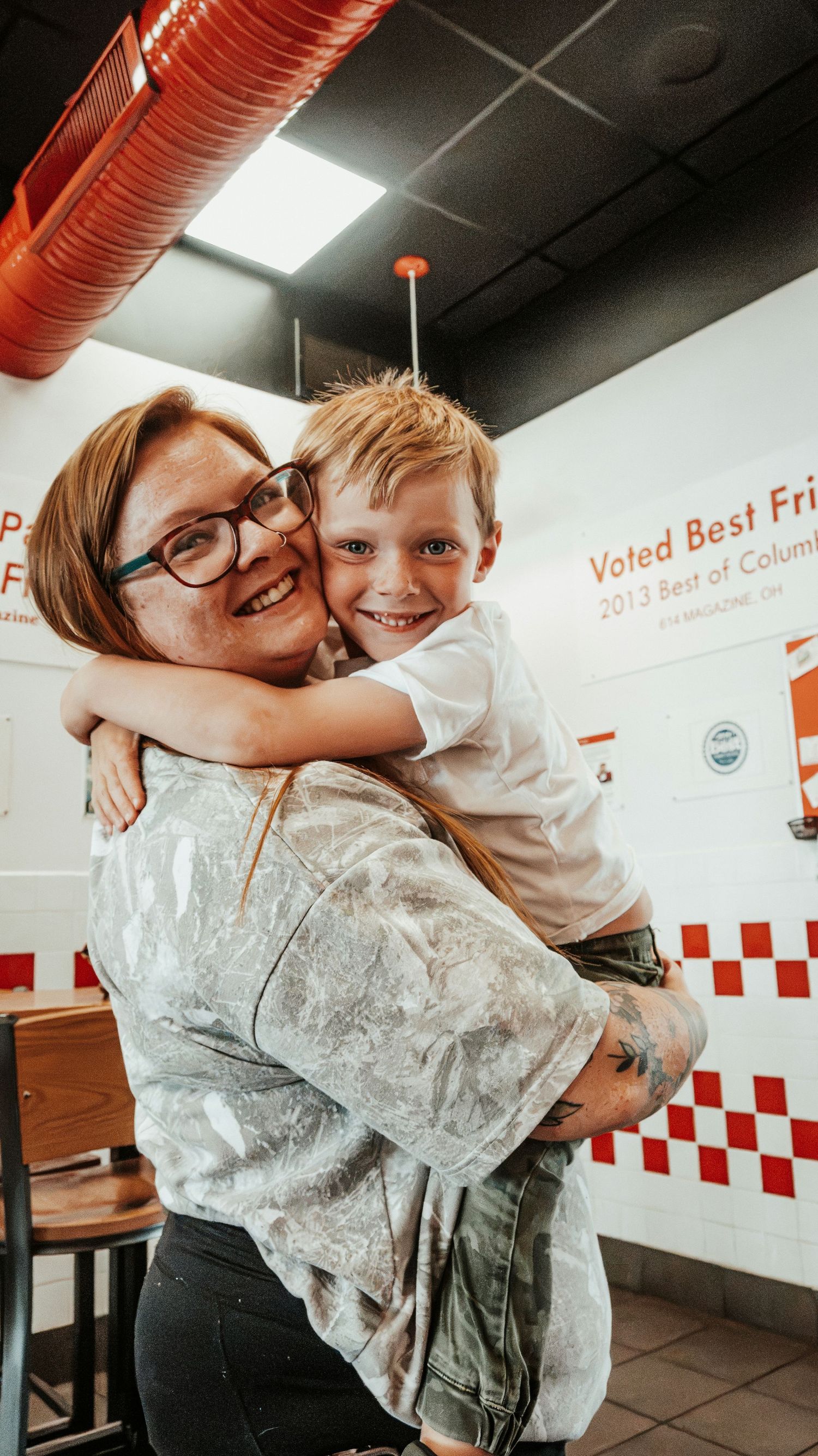 Mom hugs son at Five Guys restaurant for 5th birthday photos. Family Photographer in Pflugerville, Tx