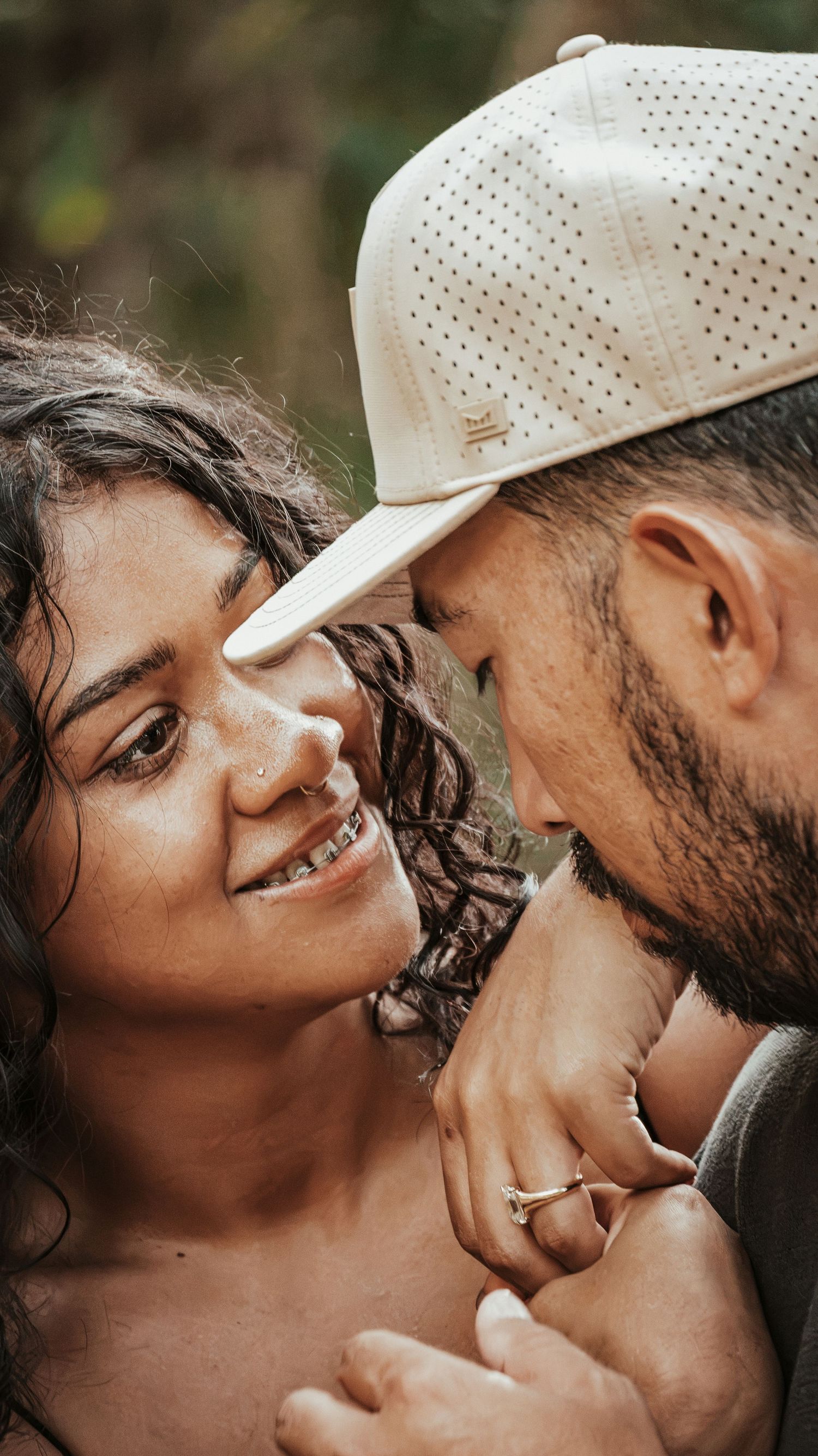 A couple shares an intimate moment, the woman smiling warmly at each other for a couples session.