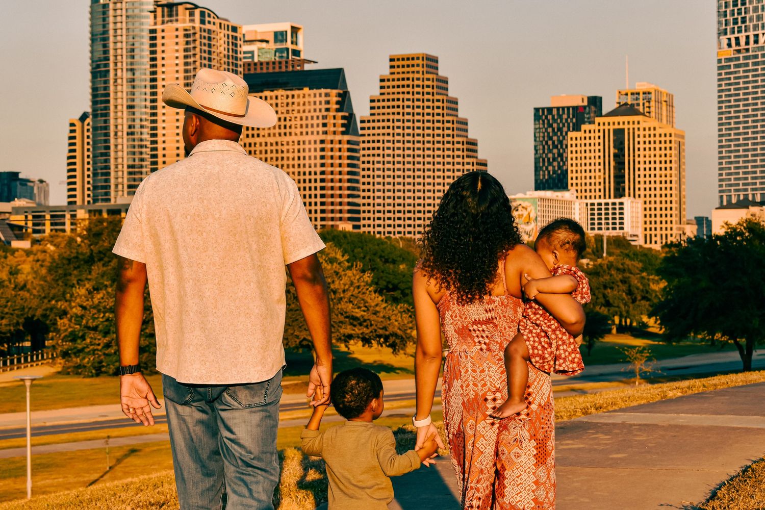 A family of four admires the Austin Texas skyline at golden hour, parents holding children while overlooking city buildings.