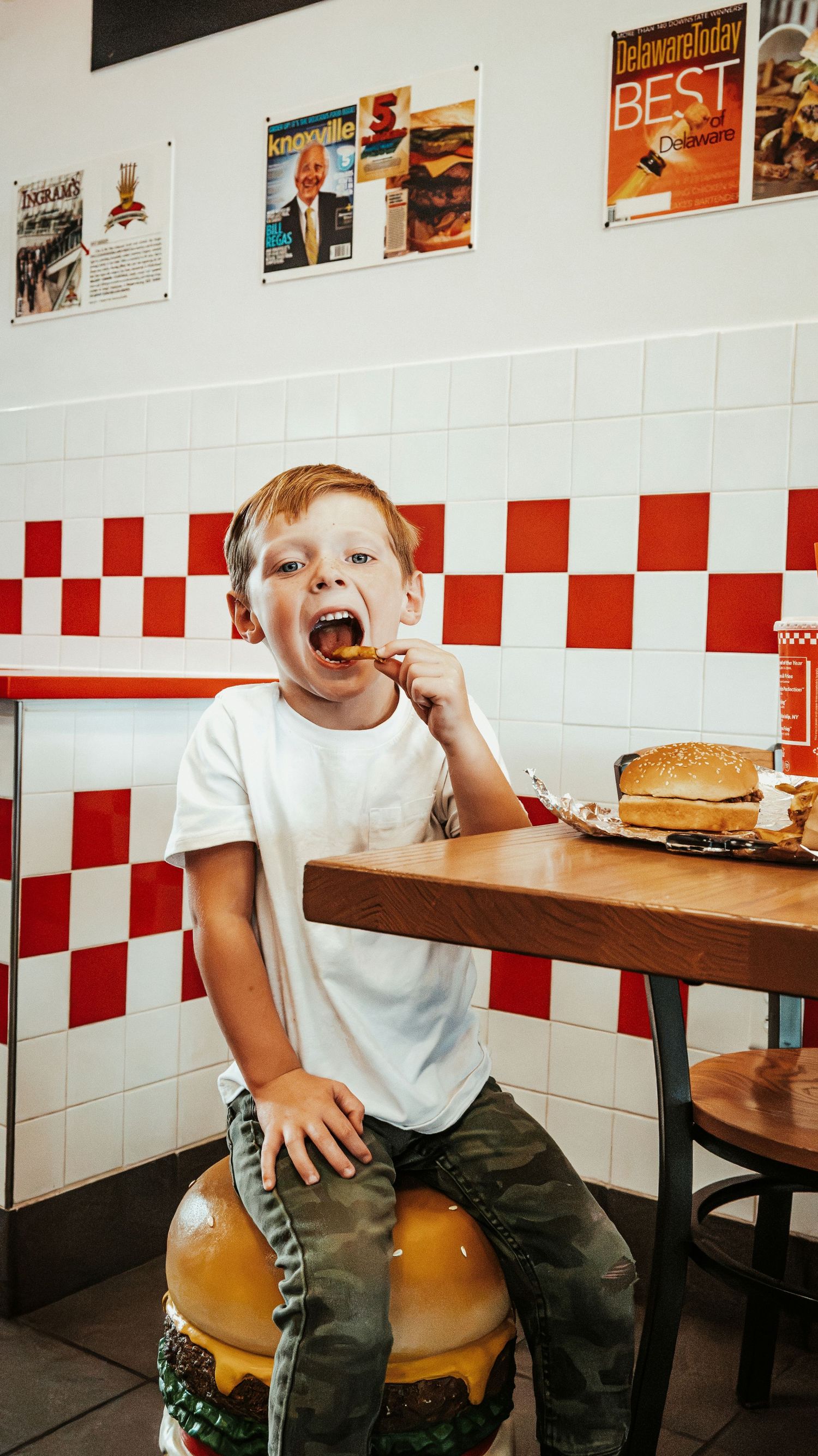Young boy eating fries on a burger stool at Five Guys restaurant. Family Photographer in Pflugerville, Tx