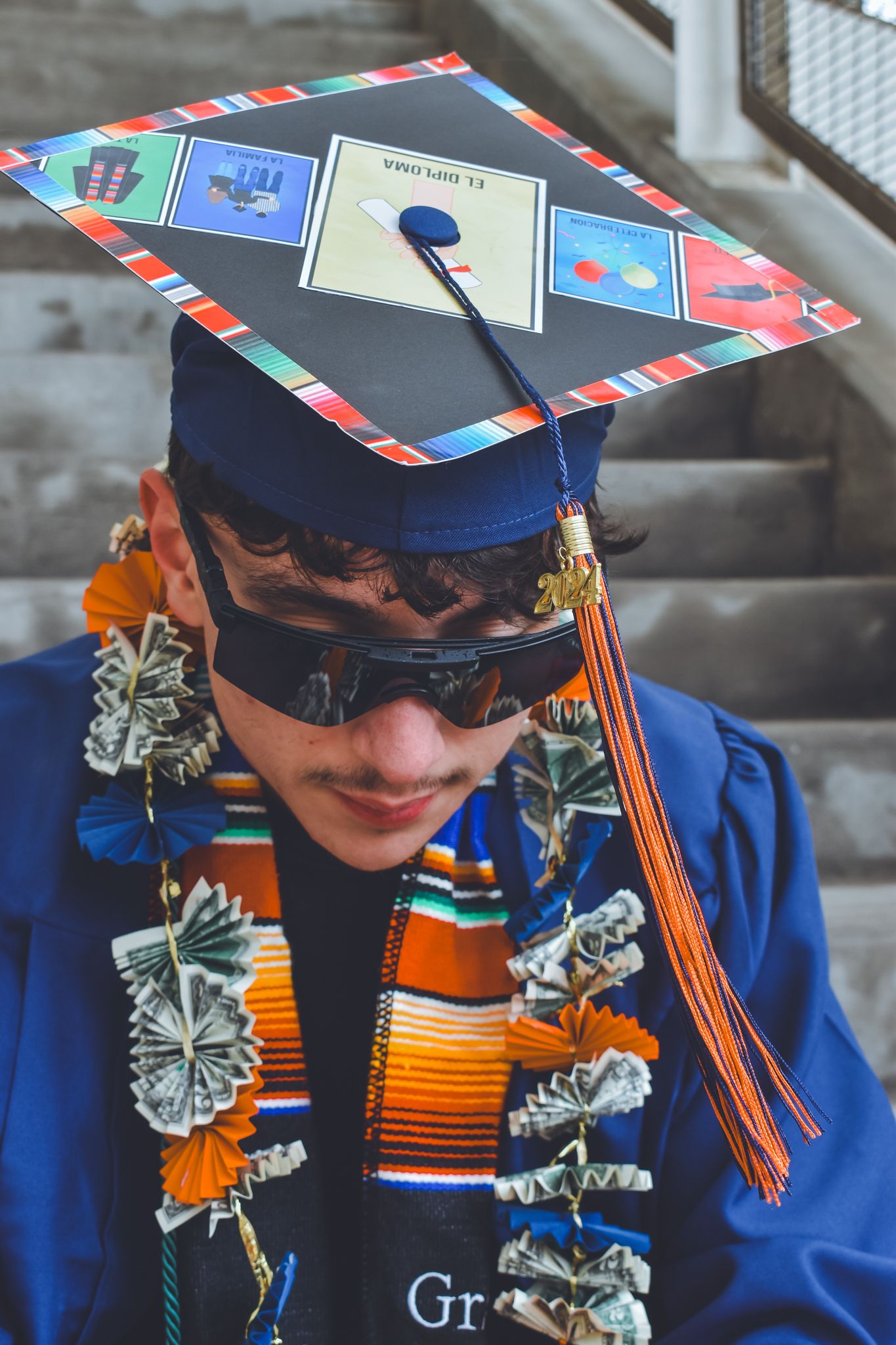 Close-up of graduate wearing decorated Loteria-themed mortarboard cap with money flower leis for senior photos.