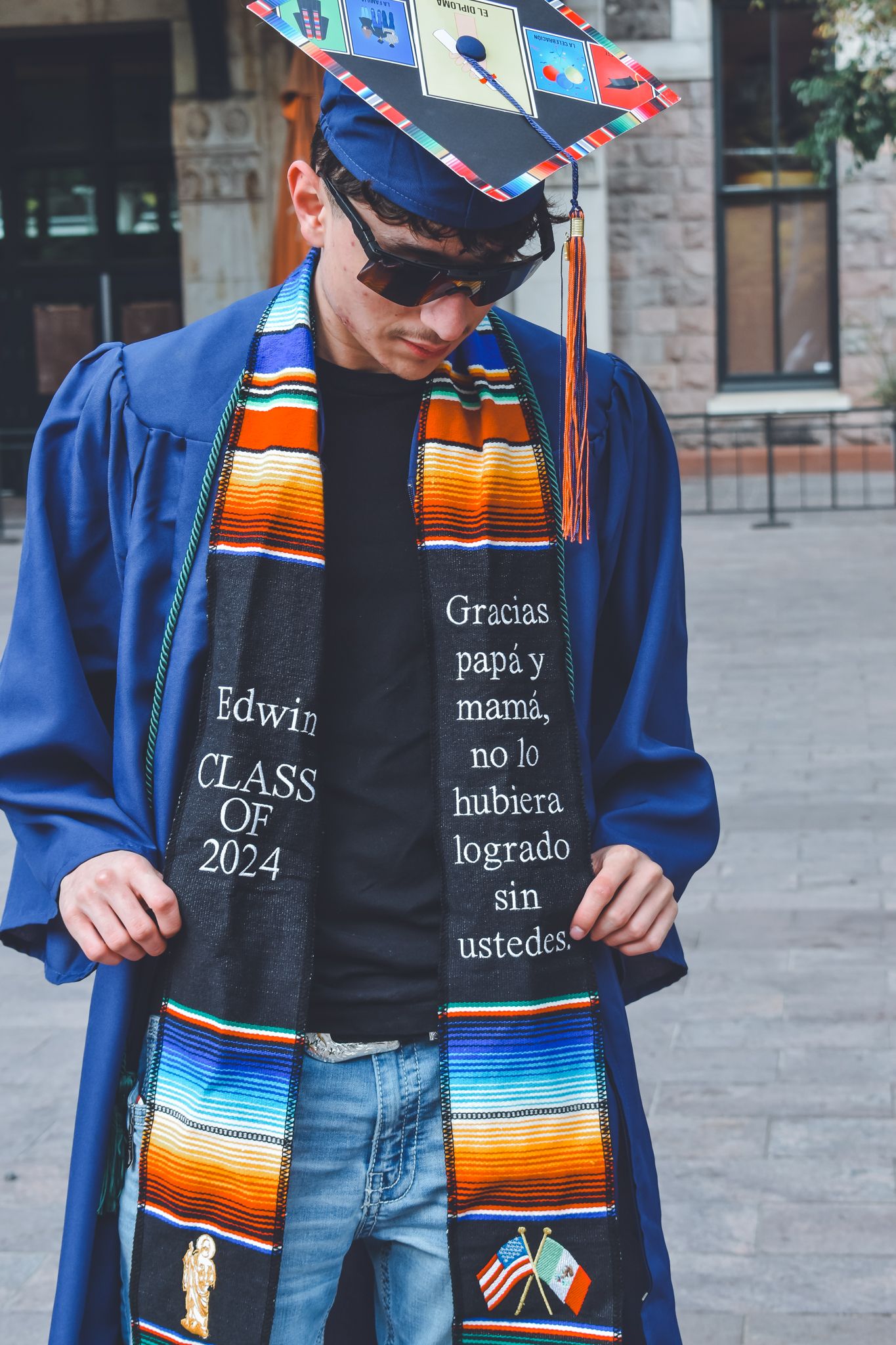 Graduate displays stole reading Edwin Class of 2024 with Spanish message to parents for senior photos.